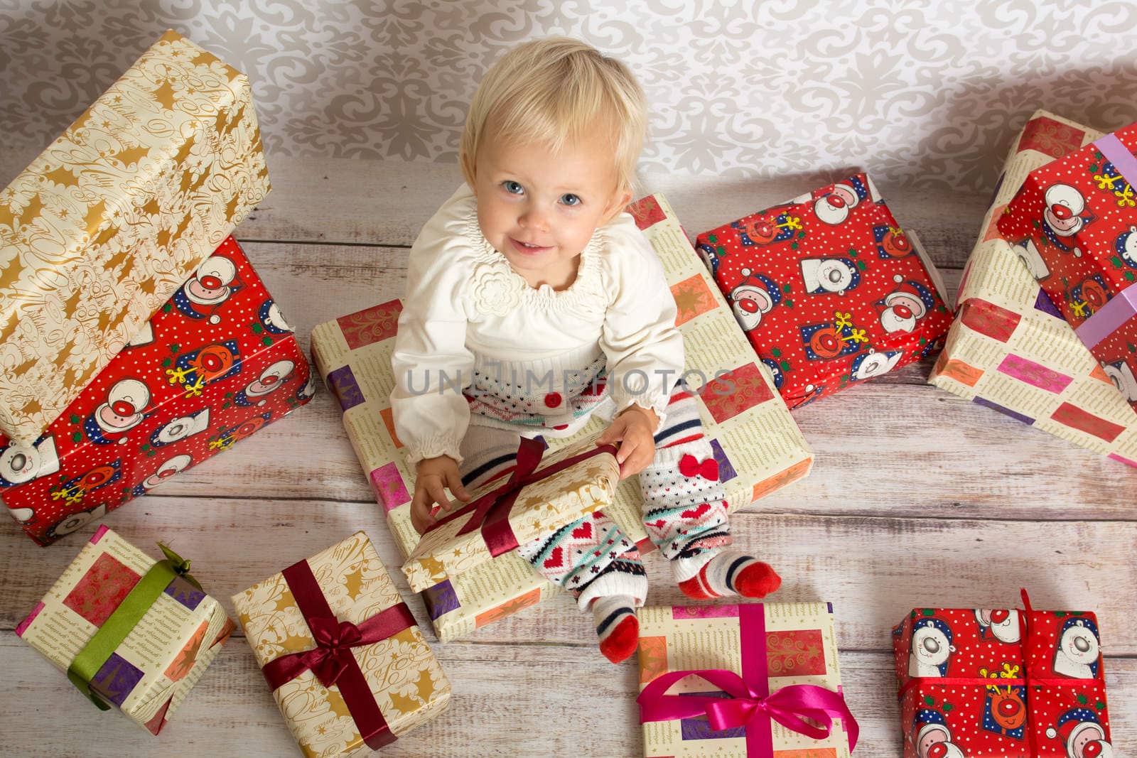 Little girl being happy ,sitting on gift box and smiling.She is  surrounded by more gift boxes