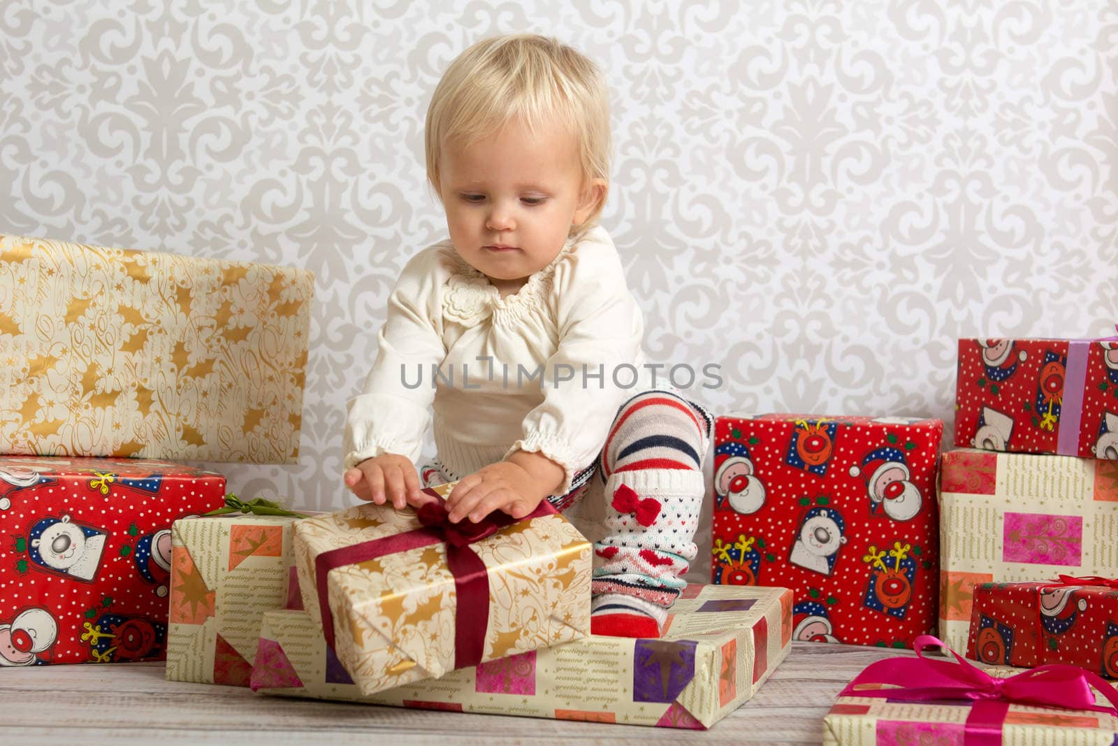 An adorable baby girl concentrate when unwrapping Christmas gift