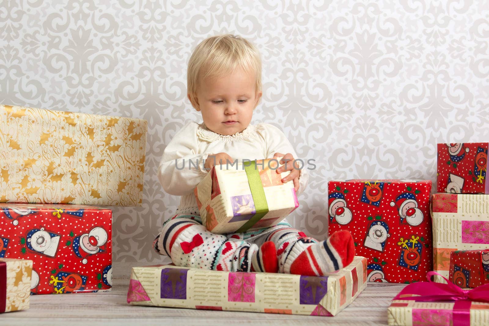 An adorable baby girl concentrate when holding a wrapped Christmas gift