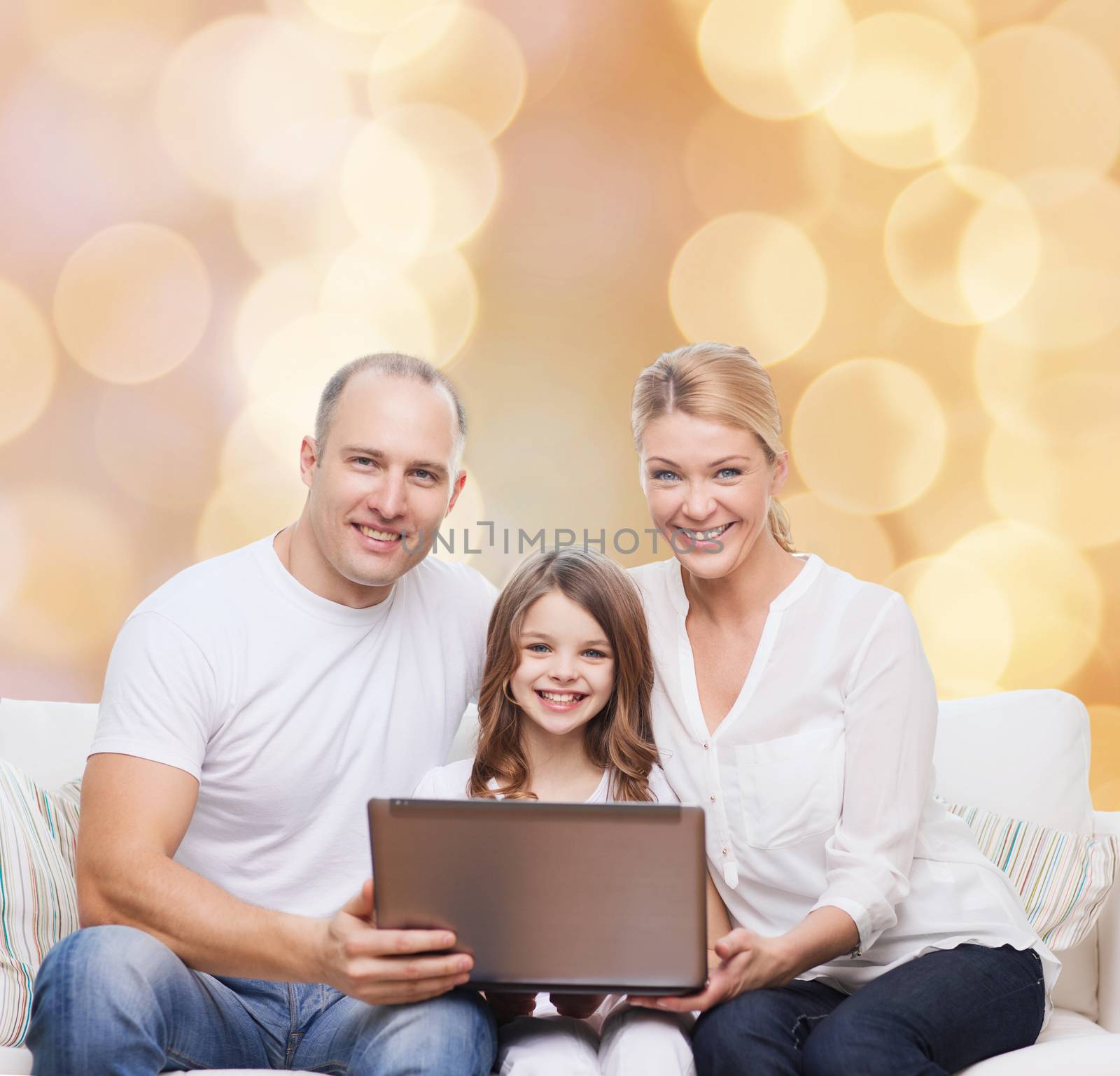 family, childhood, holidays, technology and people concept - smiling family with laptop computer over beige lights background