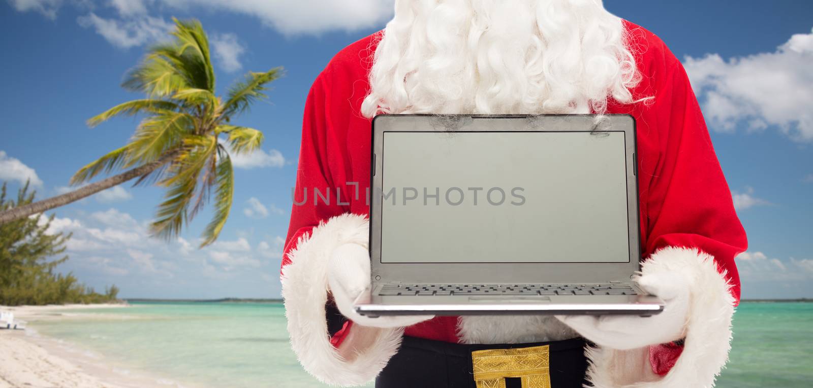 christmas, advertisement, technology, travel and people concept - close up of santa claus with laptop computer over tropical beach background