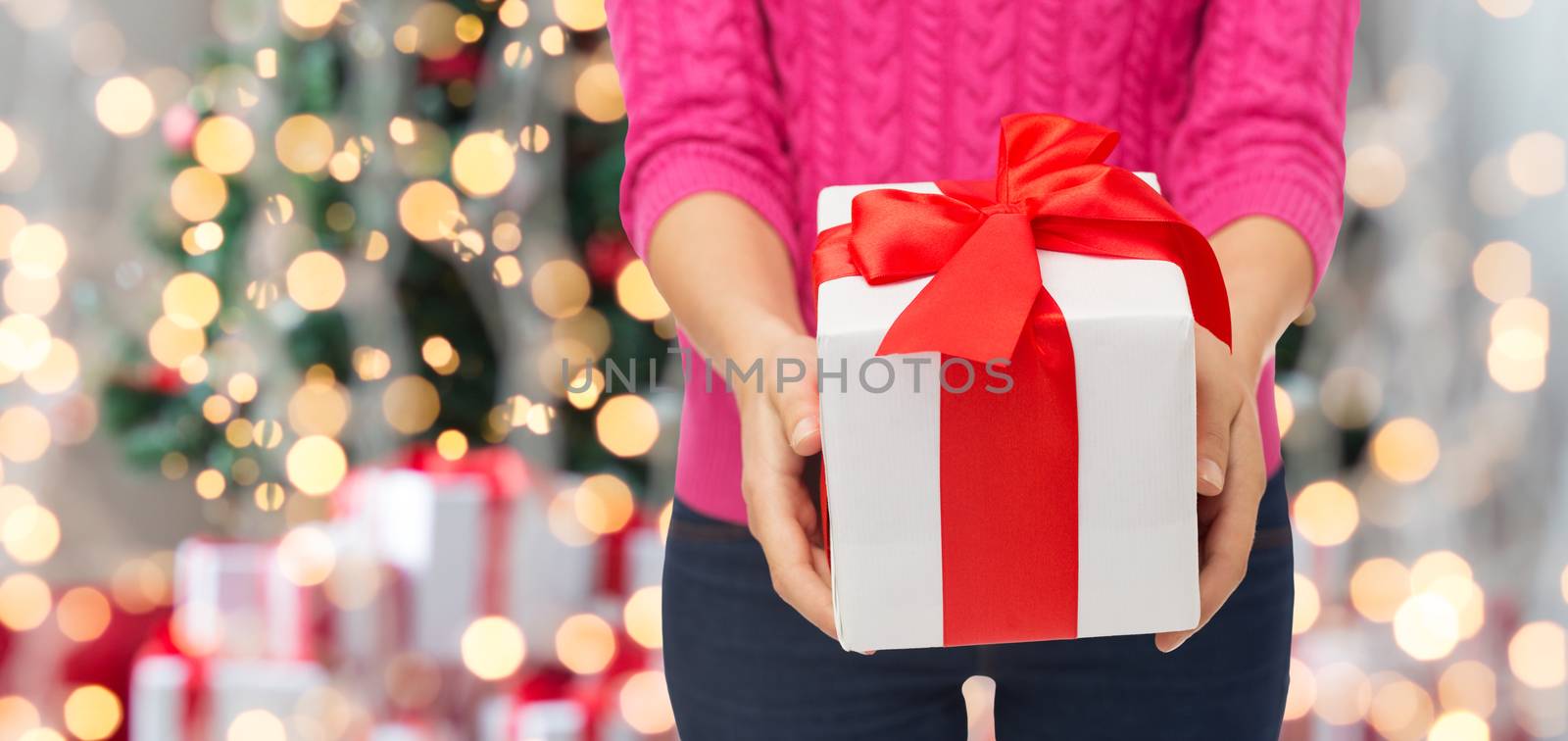 close up of woman in pink sweater holding gift box by dolgachov