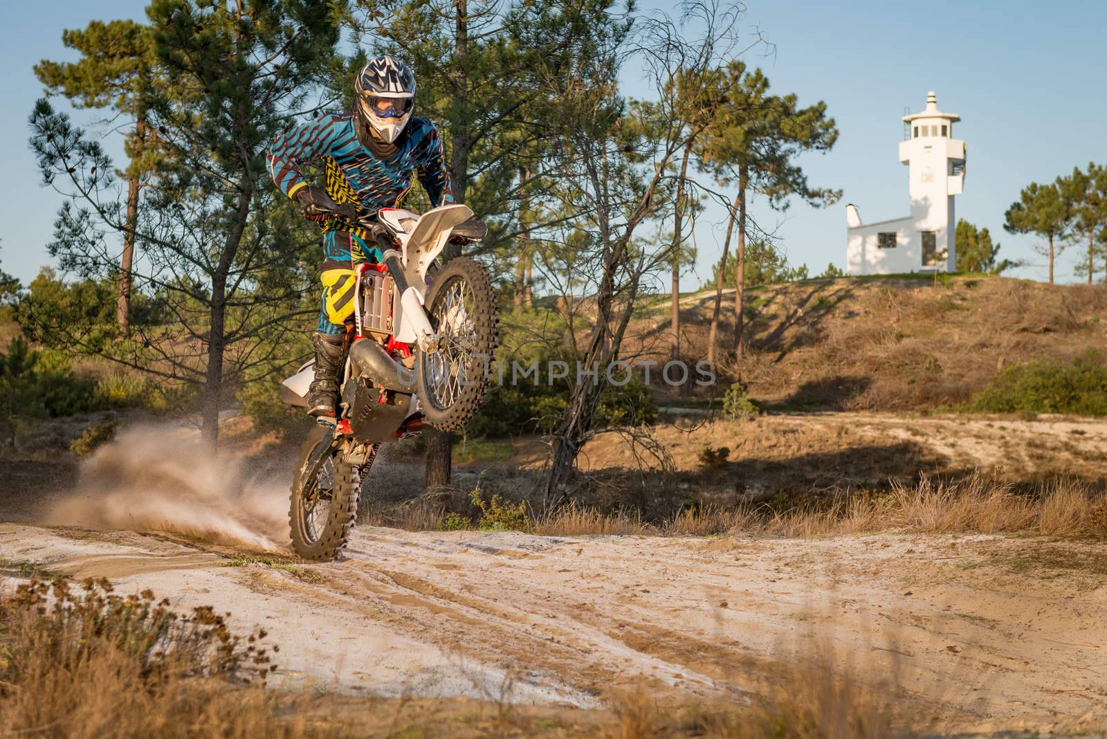Enduro bike rider on action. Wheelie on sand terrain.