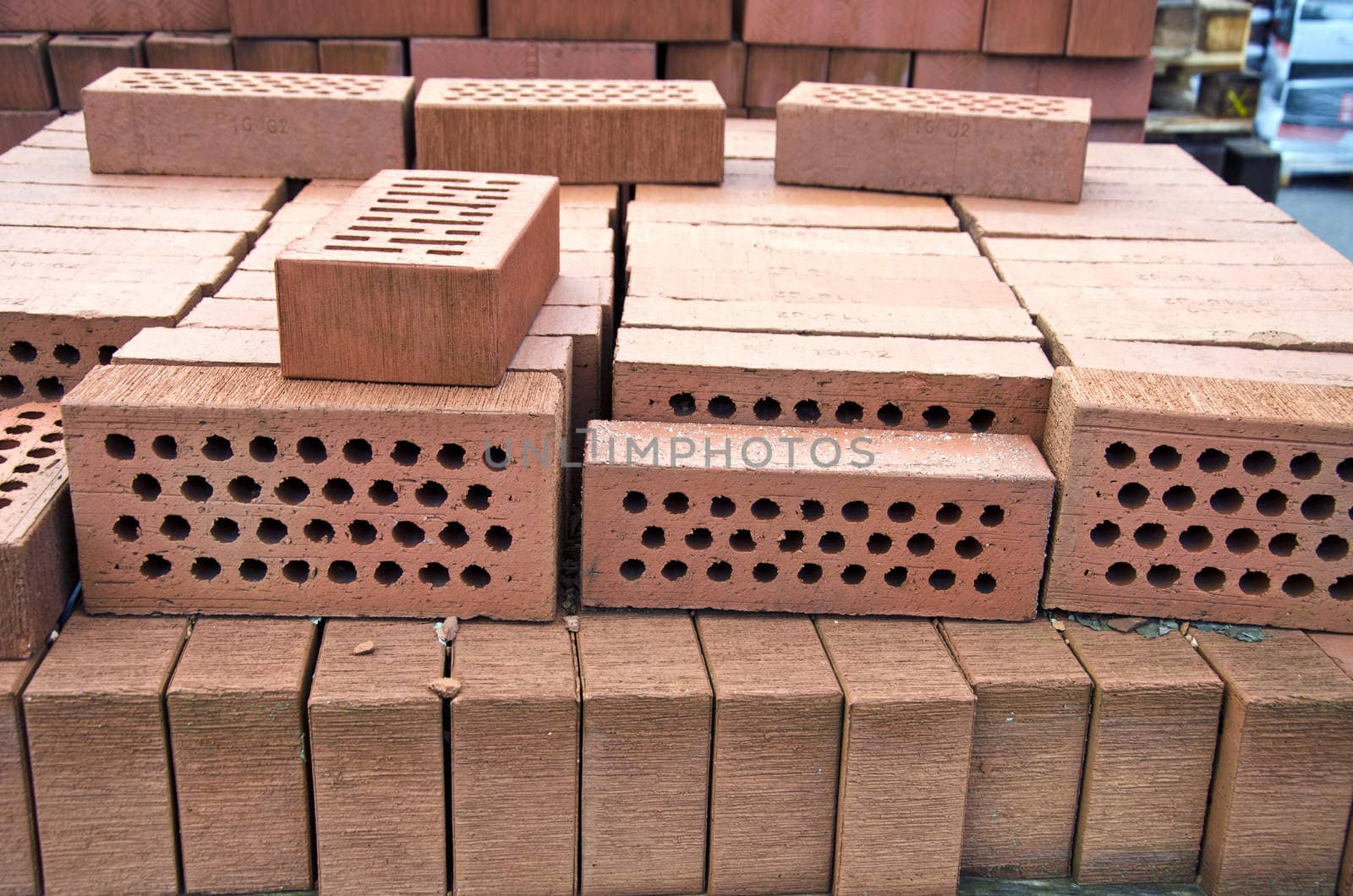 Stack of red clay bricks with holes in market