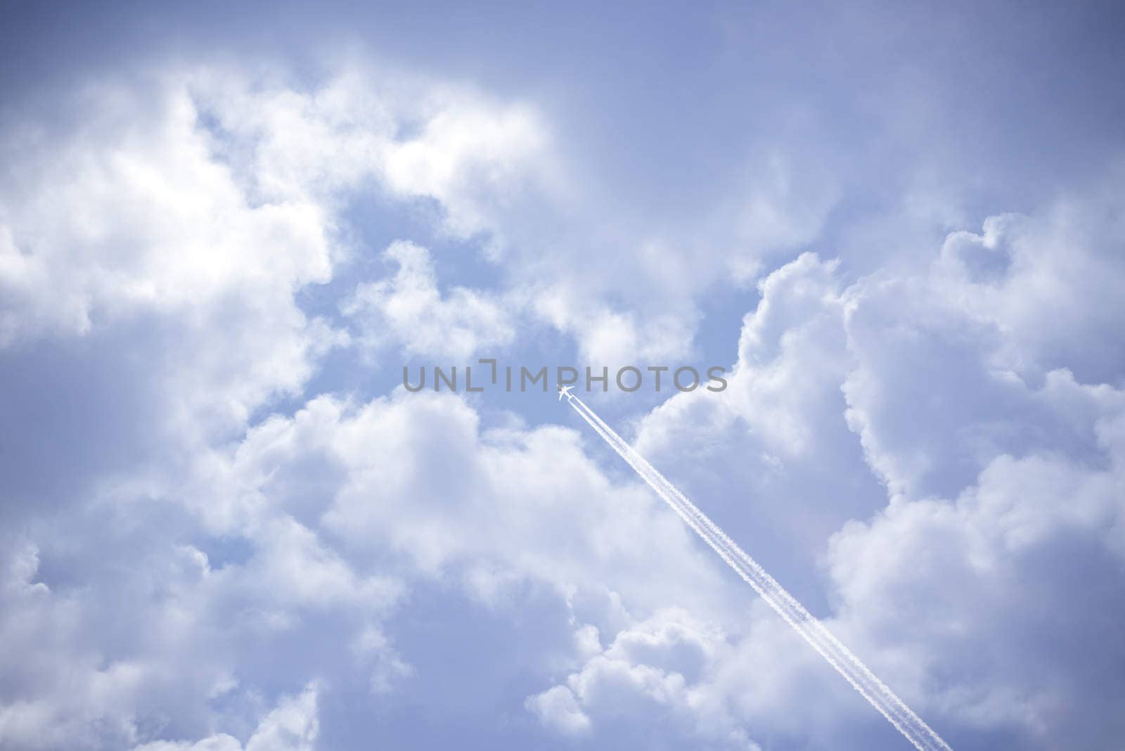 jet and its vapour trails in a cloudy blue sky