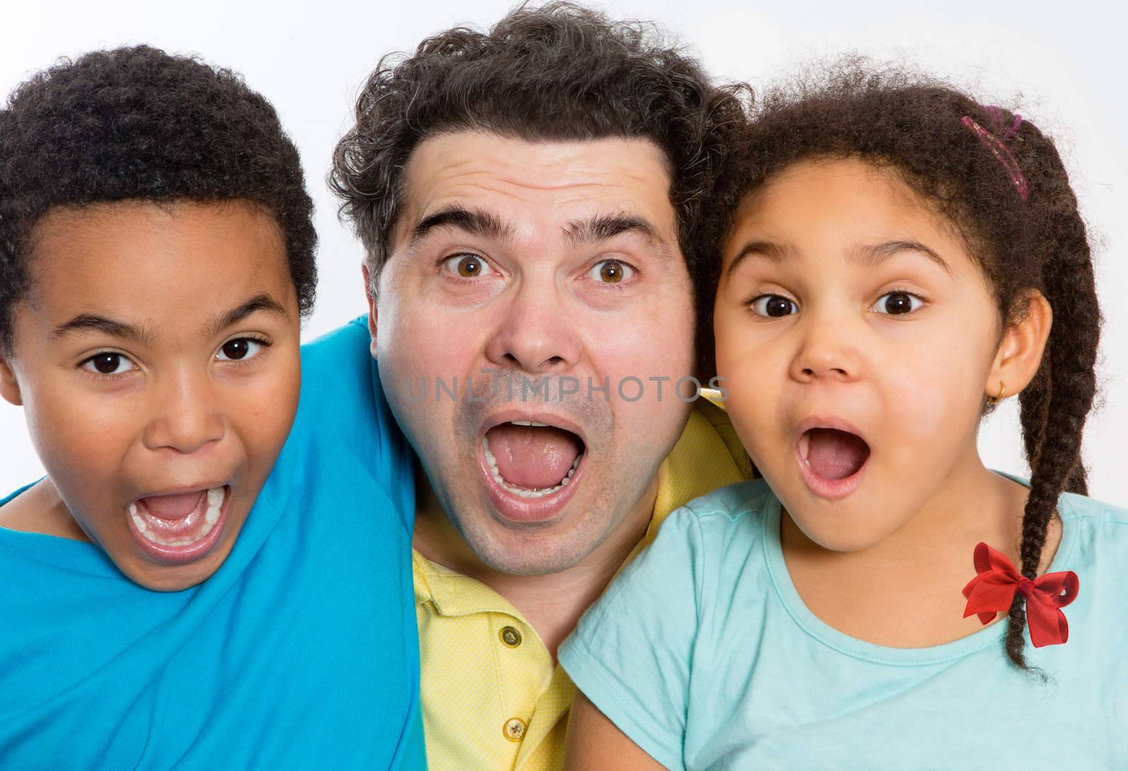 Close up Surprised Dad with Two Cute Kids Looking at the Camera with Mouth Wide Open Against White Background, Emphasizing Multicultural Family.