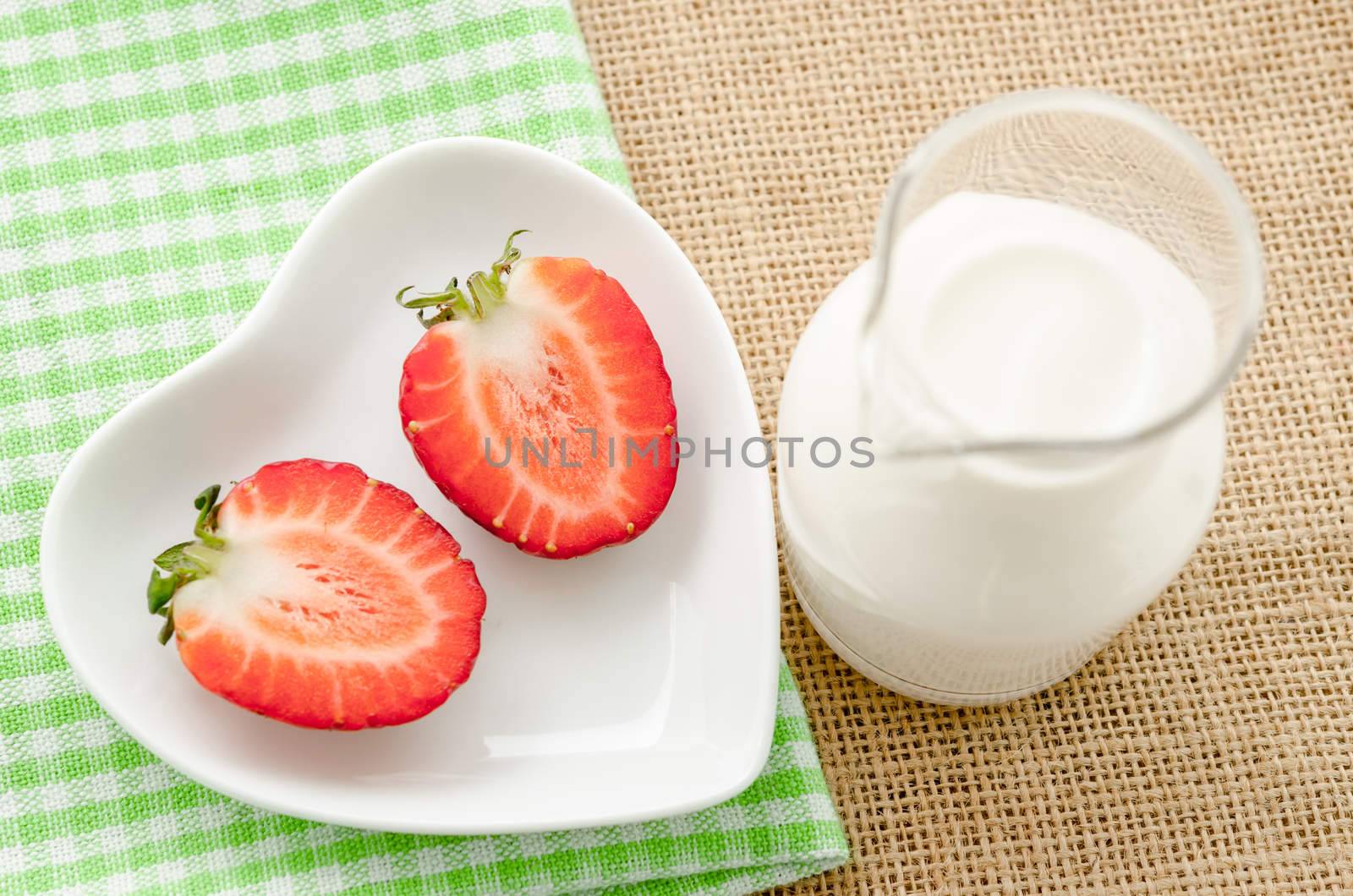 Strawberries and milk drink in glass on tablecloth and sack background.