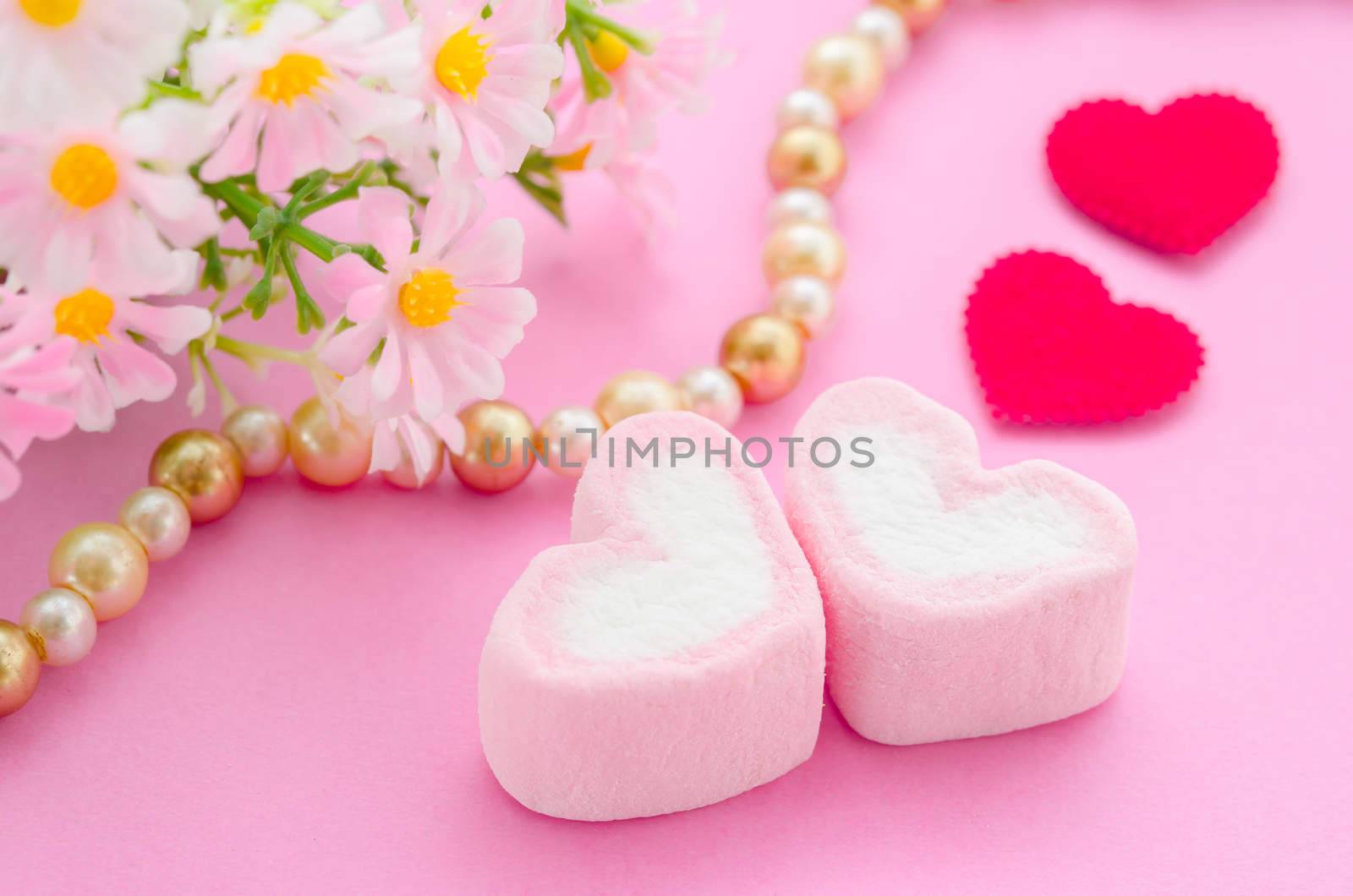 Pink marshmallow herat shape with red paper heart and flower on pink background. Love concept.