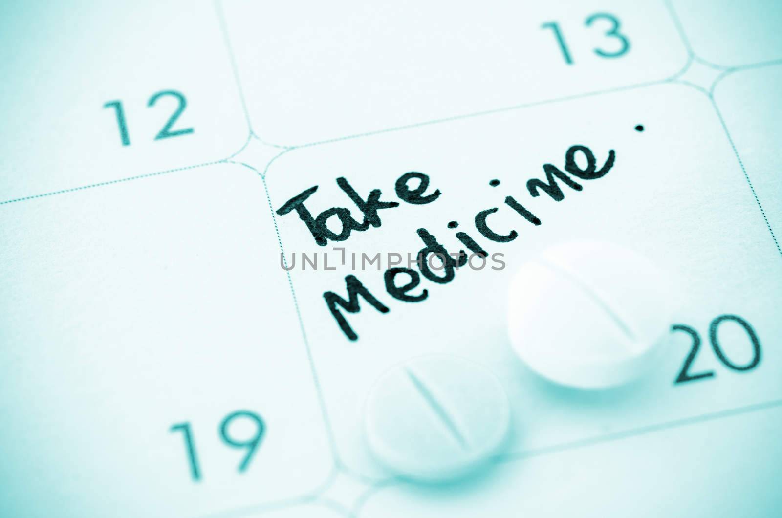 Reminder take medicine written and Medicine pills on calendar.