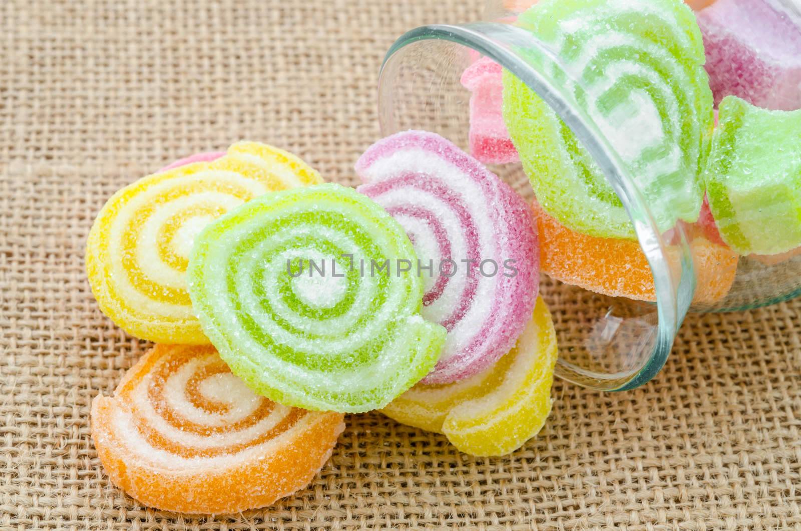 Sweet sugar candies in glass bottle on sack background.