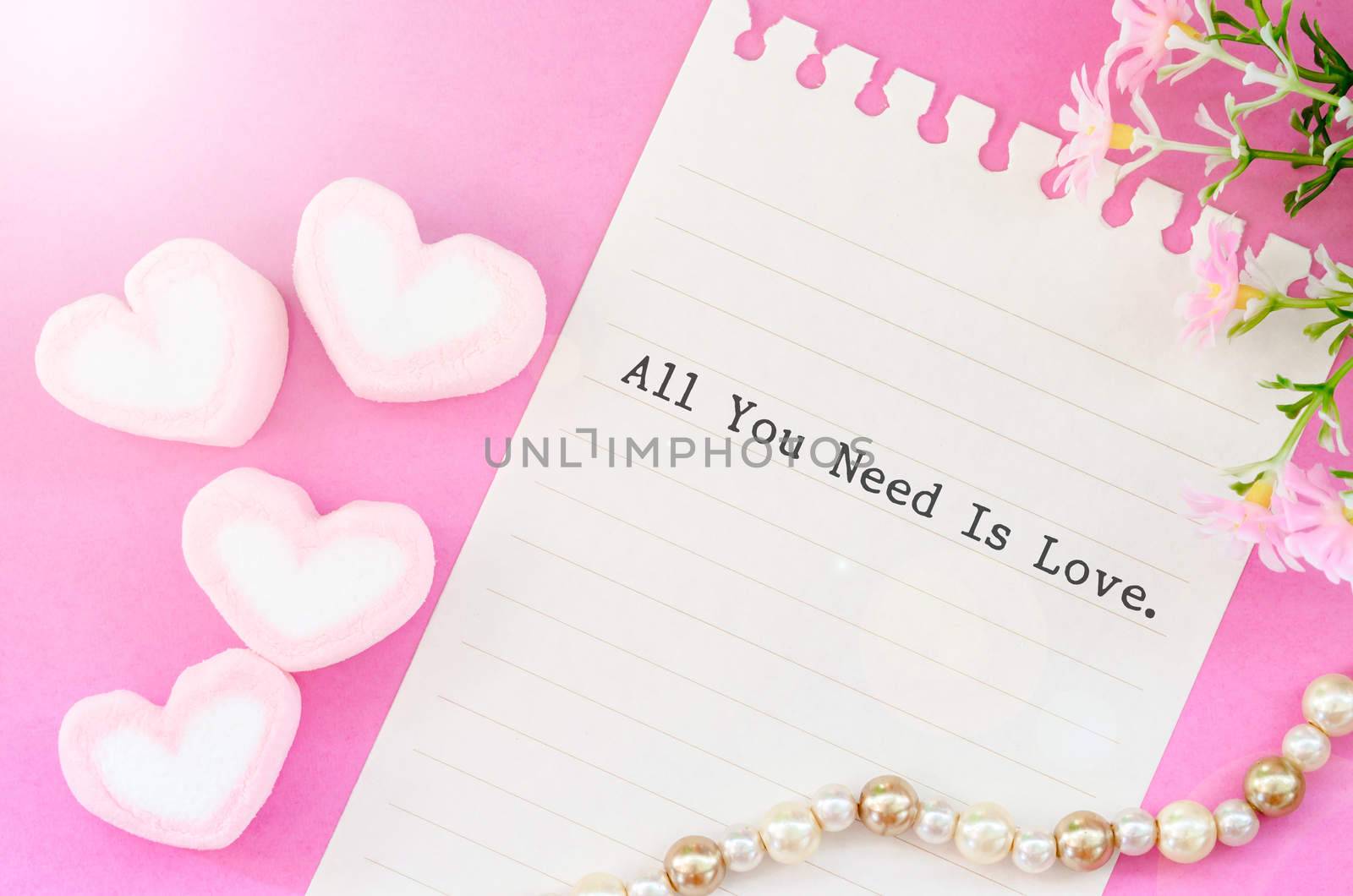 All you need is love with sweet heart shape of pink marshmallows with flower on pink background.