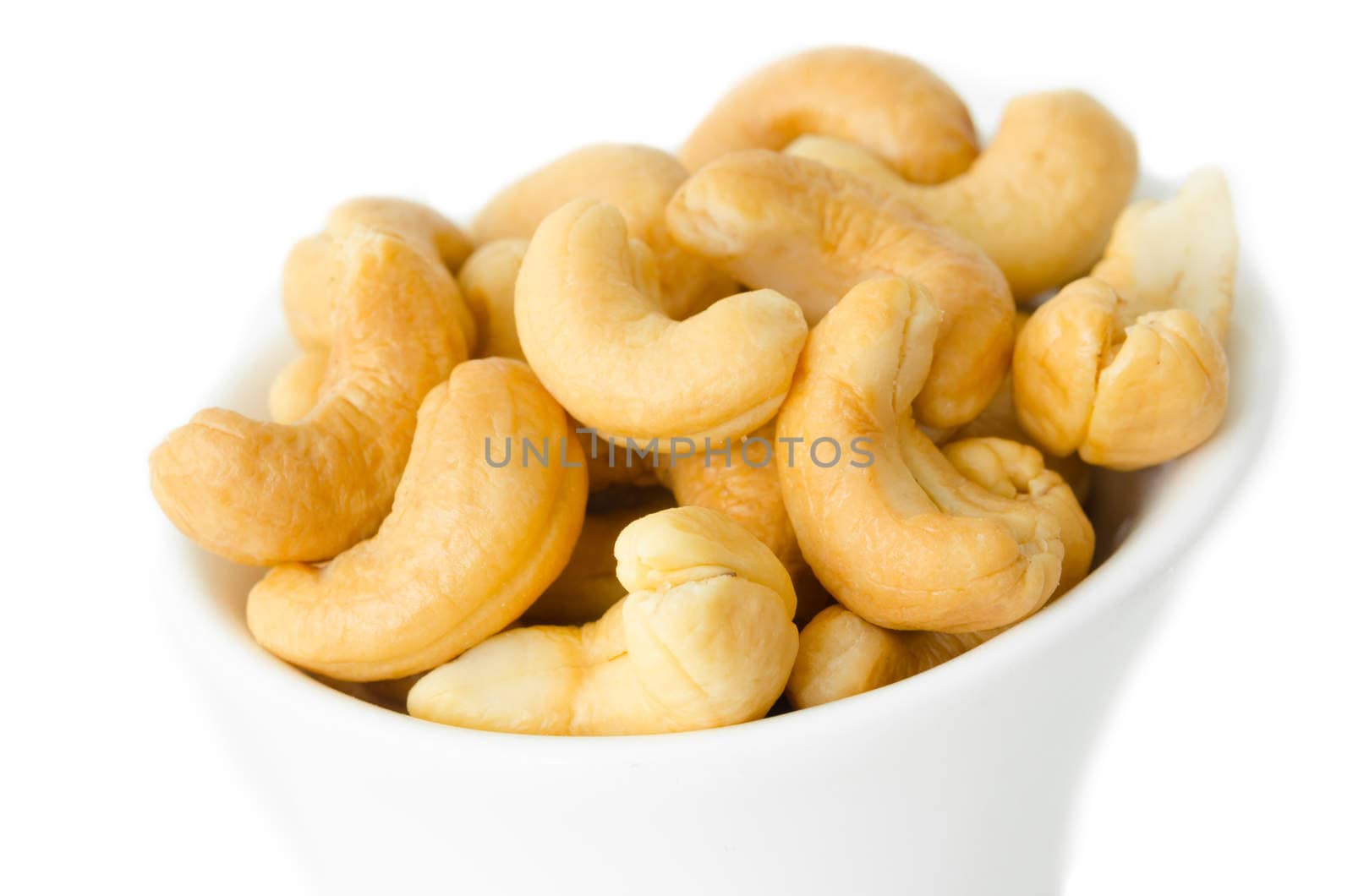Cashew nuts in a white bowl. Isolated on white.