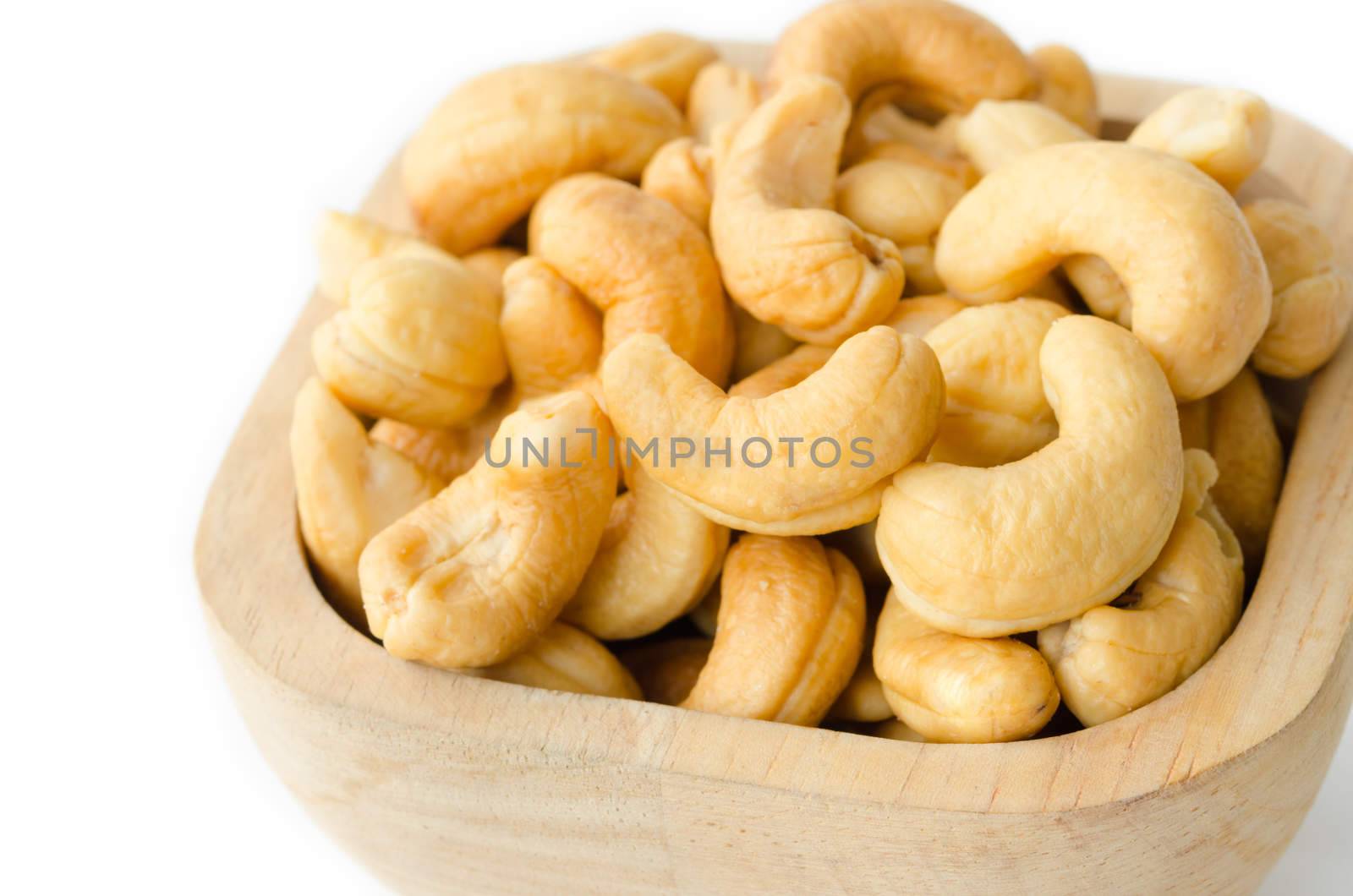 Roasted cashews nuts in wooden bowl on white background.