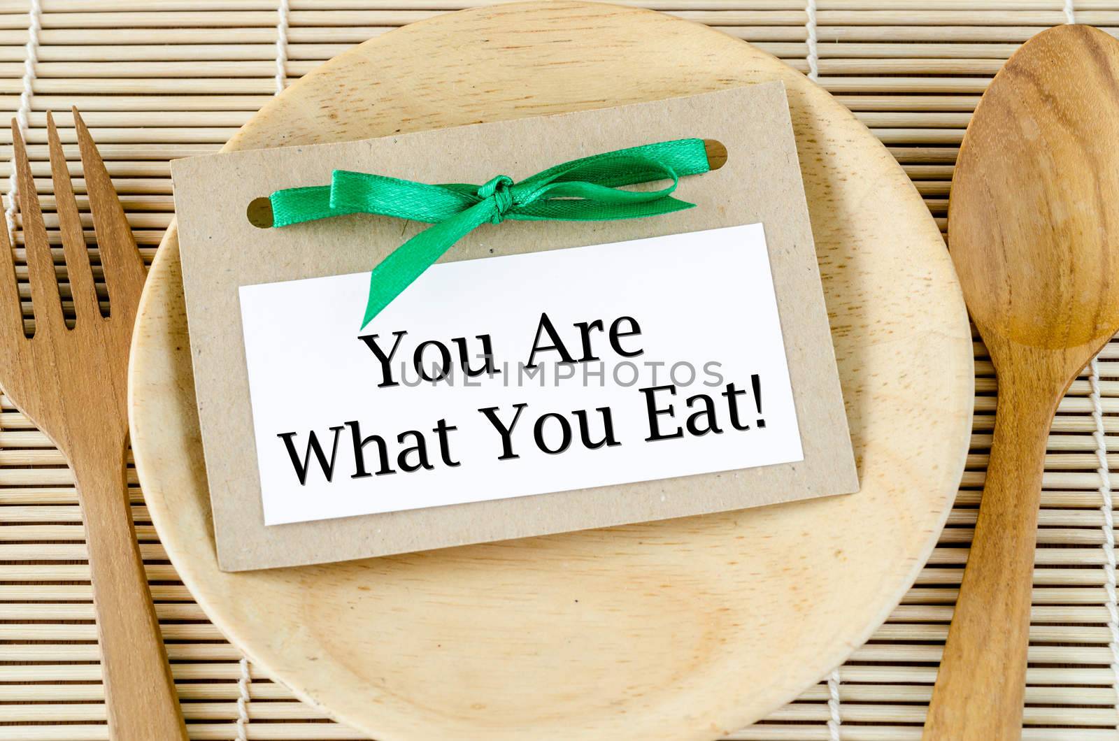 Healthy lifestyle concept - you are what to eat reminder words in paper tag on dish and spoon wooden.