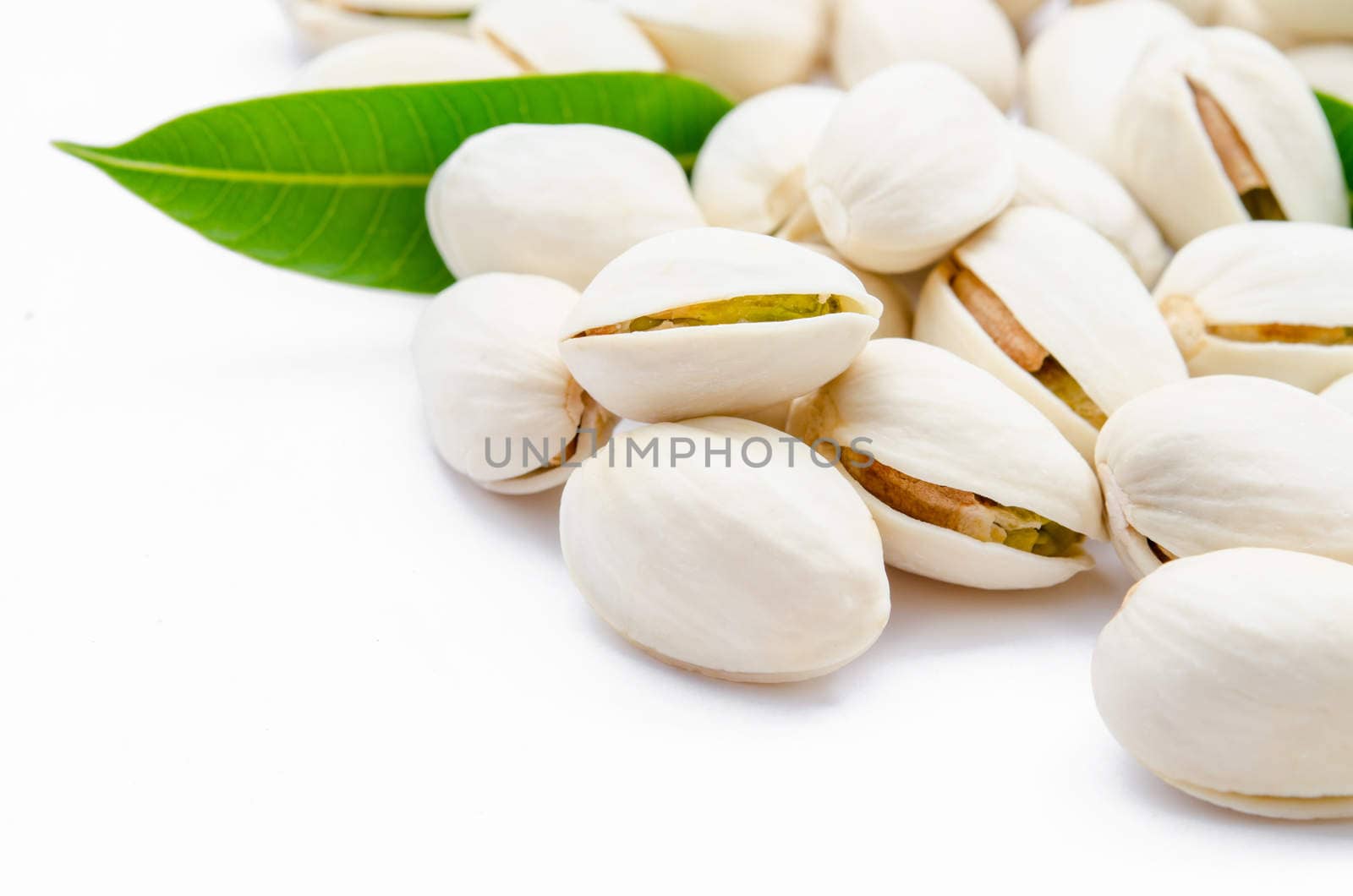 Pistachio nuts with green leaf on white background.