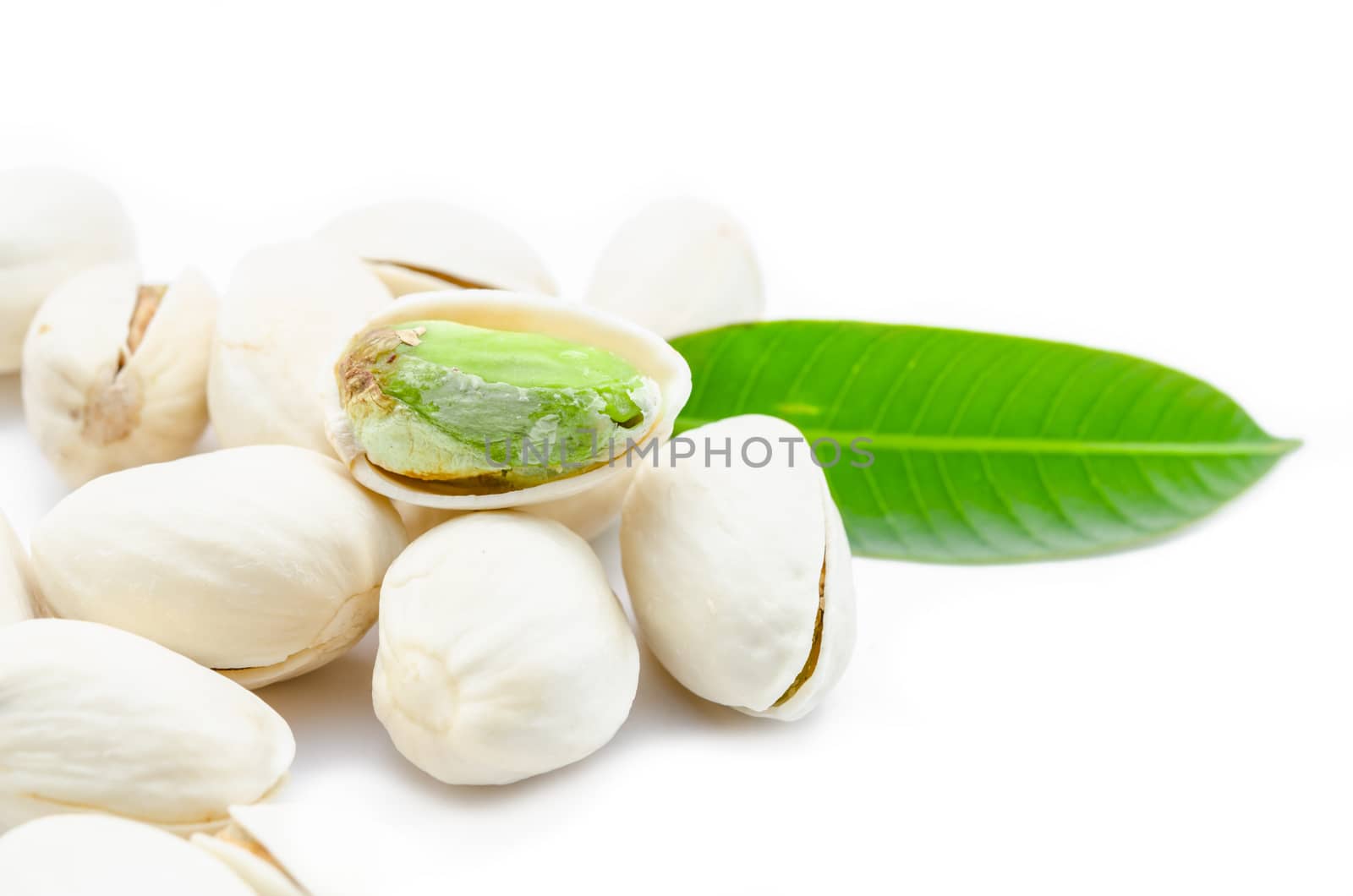 Pistachio nuts with green leaf on white background.