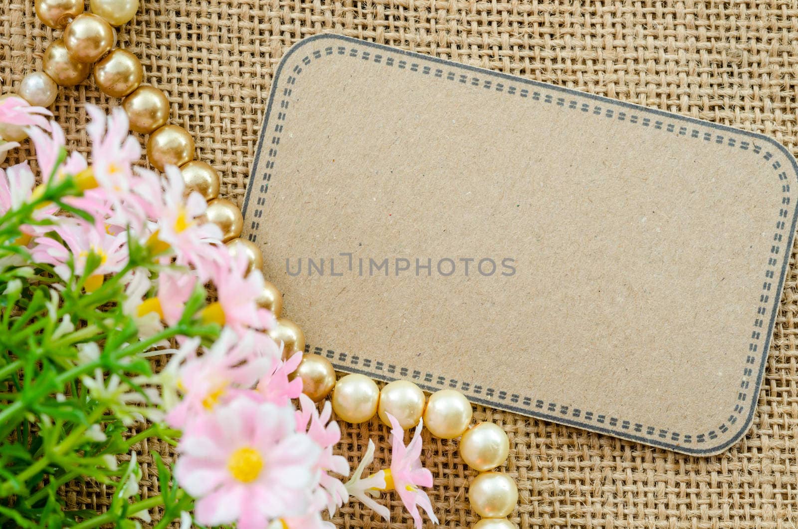 Blank brown tag paper with flower on sack background for your text.