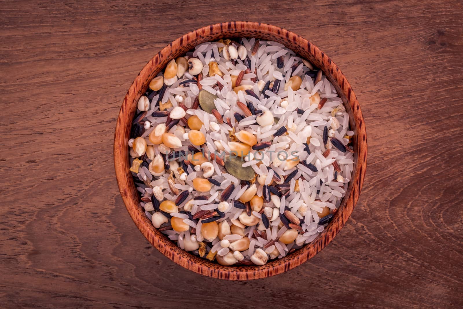 Mixed Whole grain Traditional Thai rice in the spoon and bowl best rice for healthy and clean food on teak wood background.