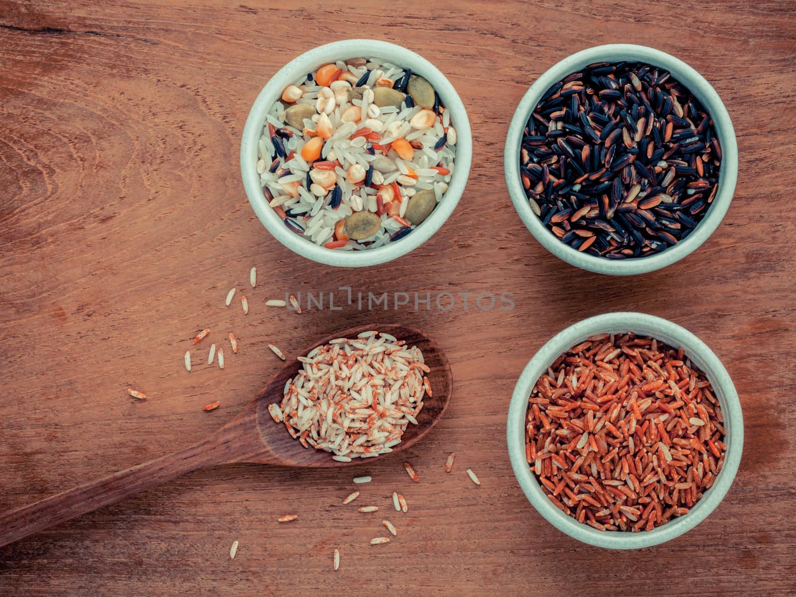 Mixed Whole grain Traditional Thai rice in the spoon and bowl best rice for healthy and clean food on teak wood background.