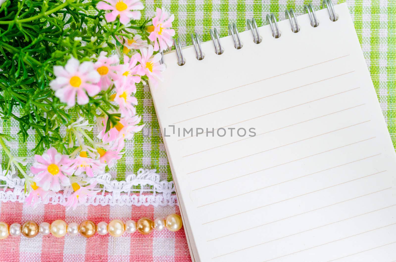 Empty notebook with beautiful flower on beautiful fabric background.