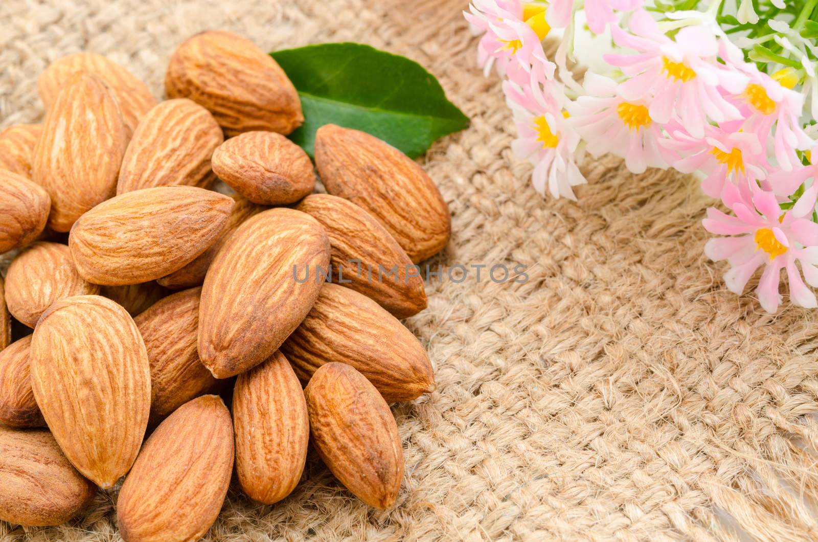 Almonds with pink flower on sack background.