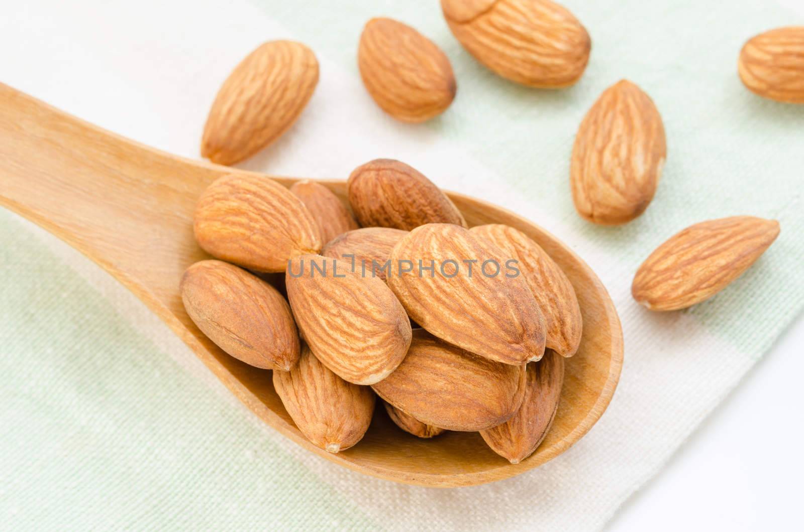 Raw Almond in wood spoon on tablecloth.