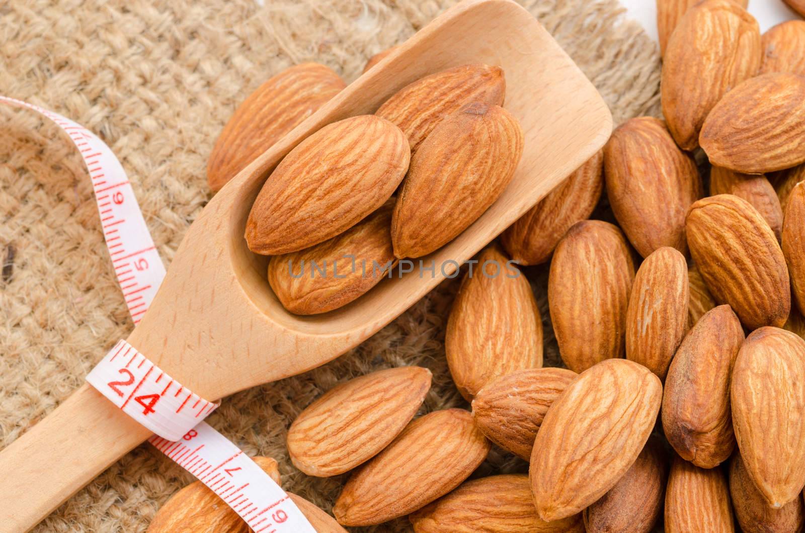 Almond in wooden spoon with measurement on sackground. Food for Diet concept.