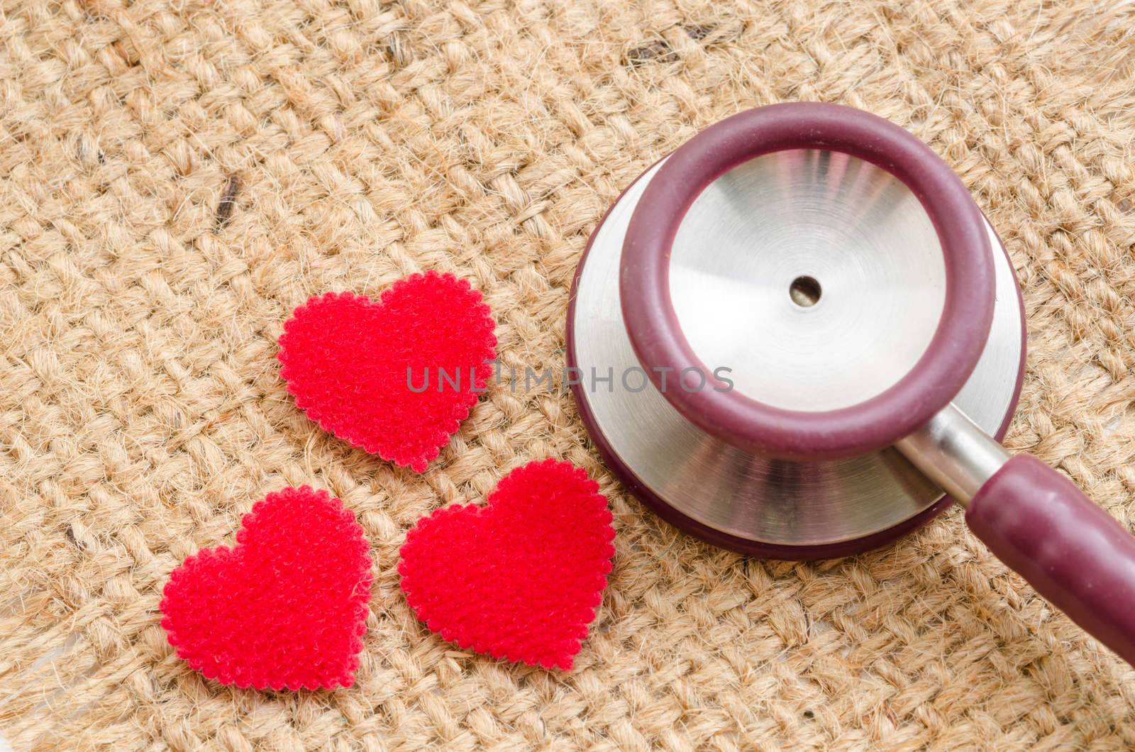 Red heart and a stethoscope on sack background.