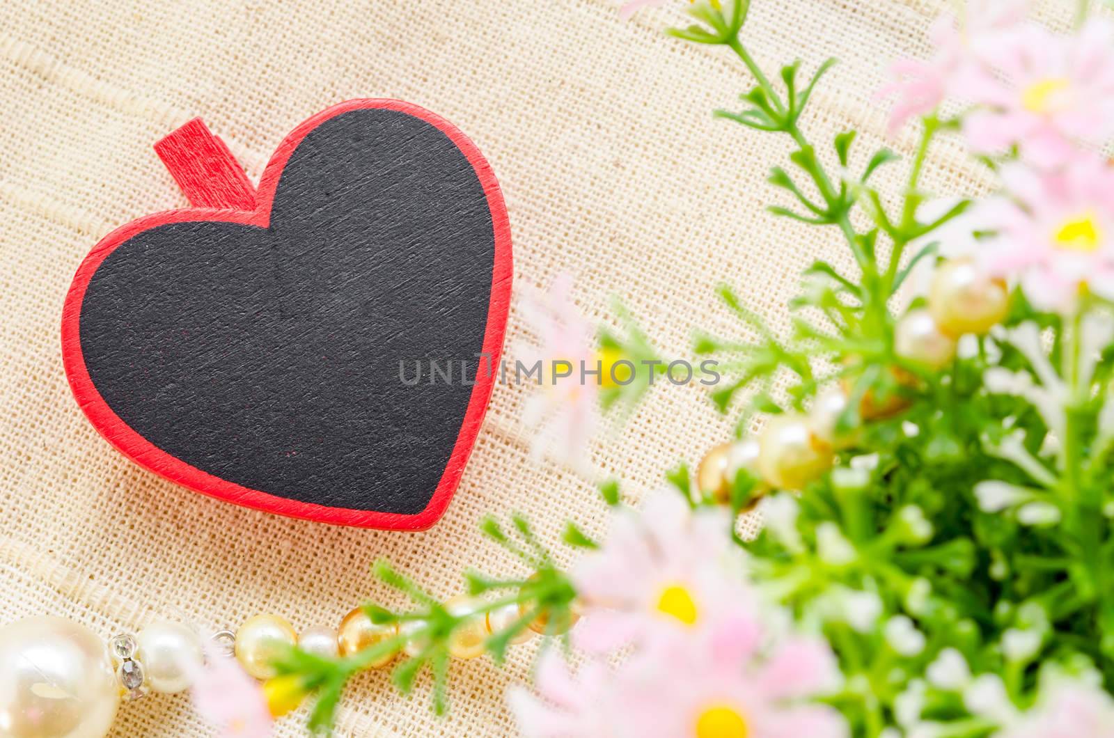 Blank wooden heart shape tag with flower on fabric background for your text. Love concept.