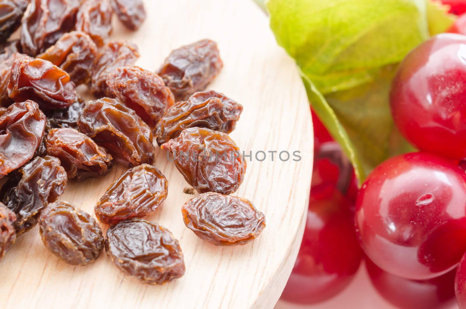 Raisins in wood with red grapes on table close up