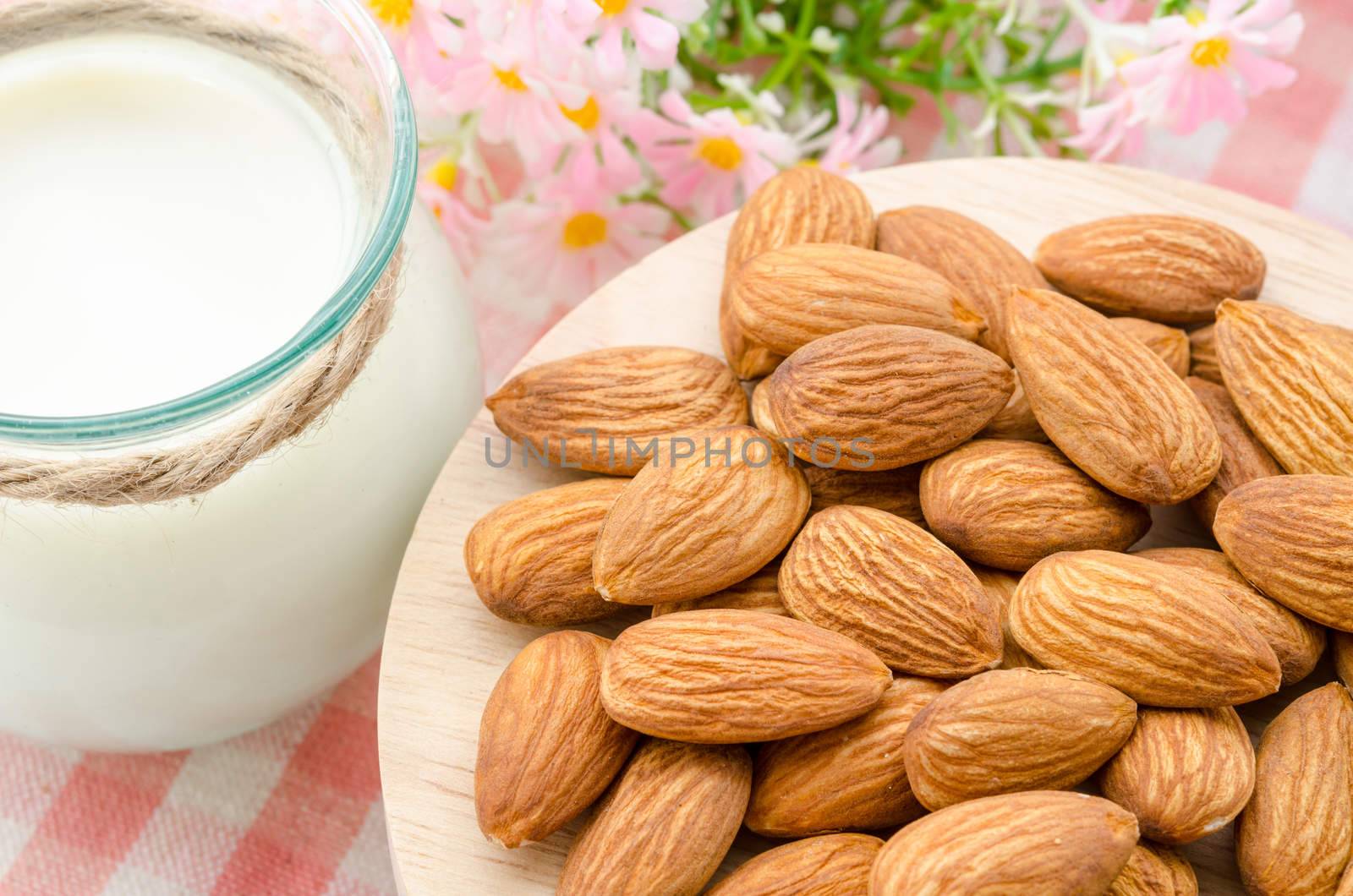 Almond with milk almond and pink flower on tablecloth.