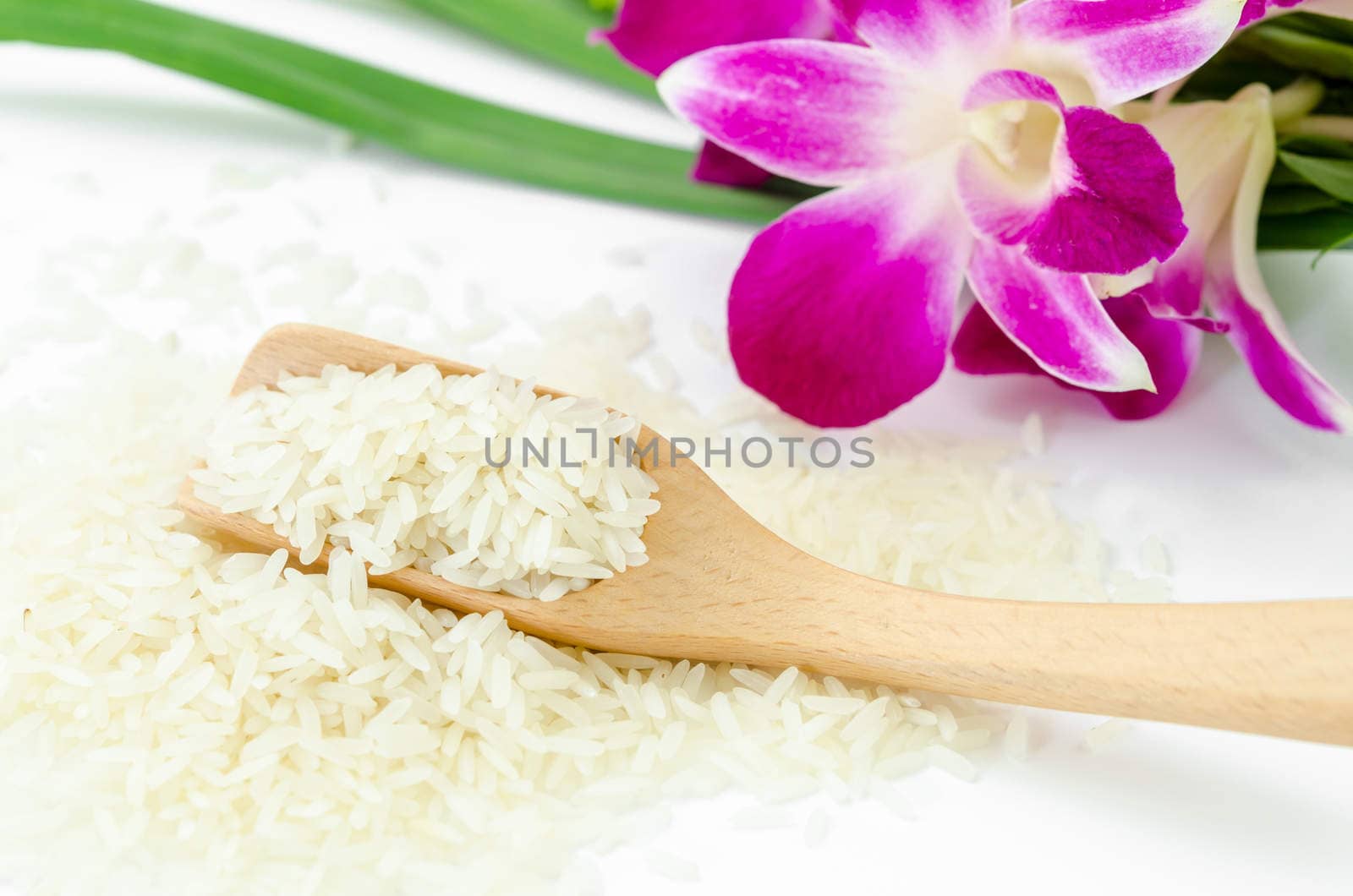 Raw rice with violet orchid flower on white background.