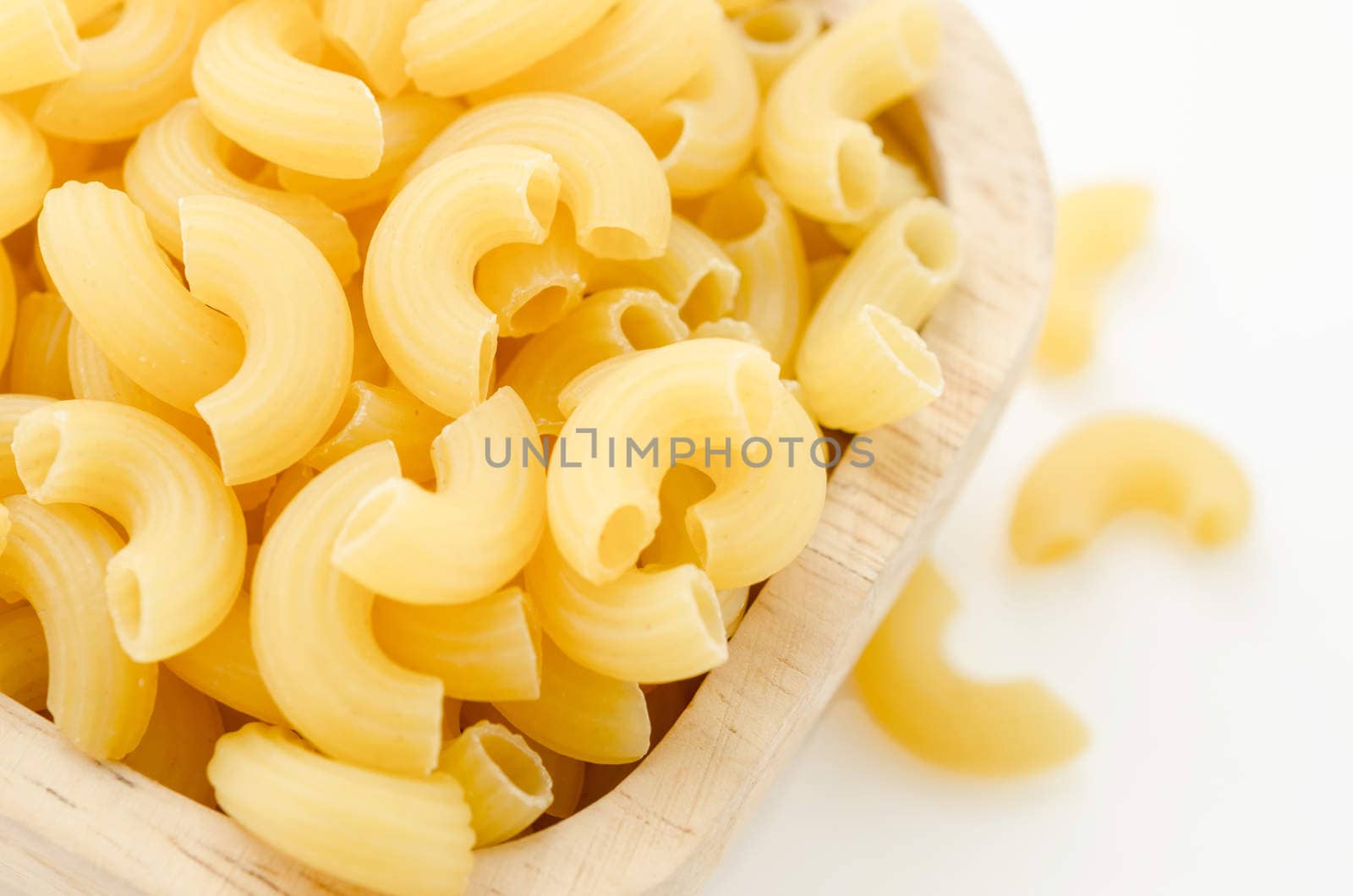 Raw dry elbow macaroni. Italian Pasta raw food in wood bowl on white background.