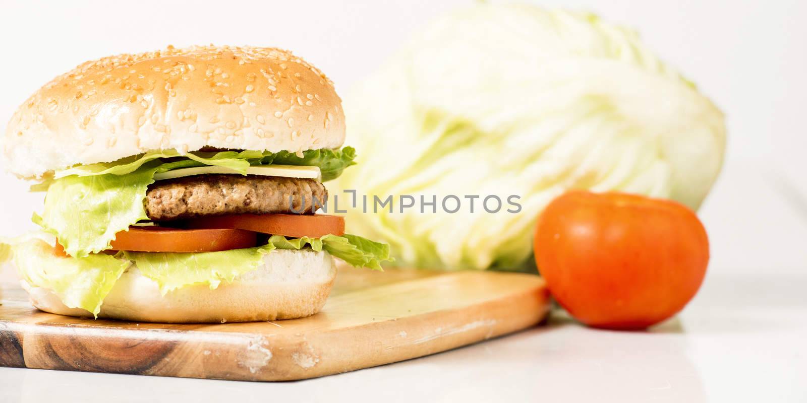 Hamburger with cheese and ingredients with a white background and timber board.