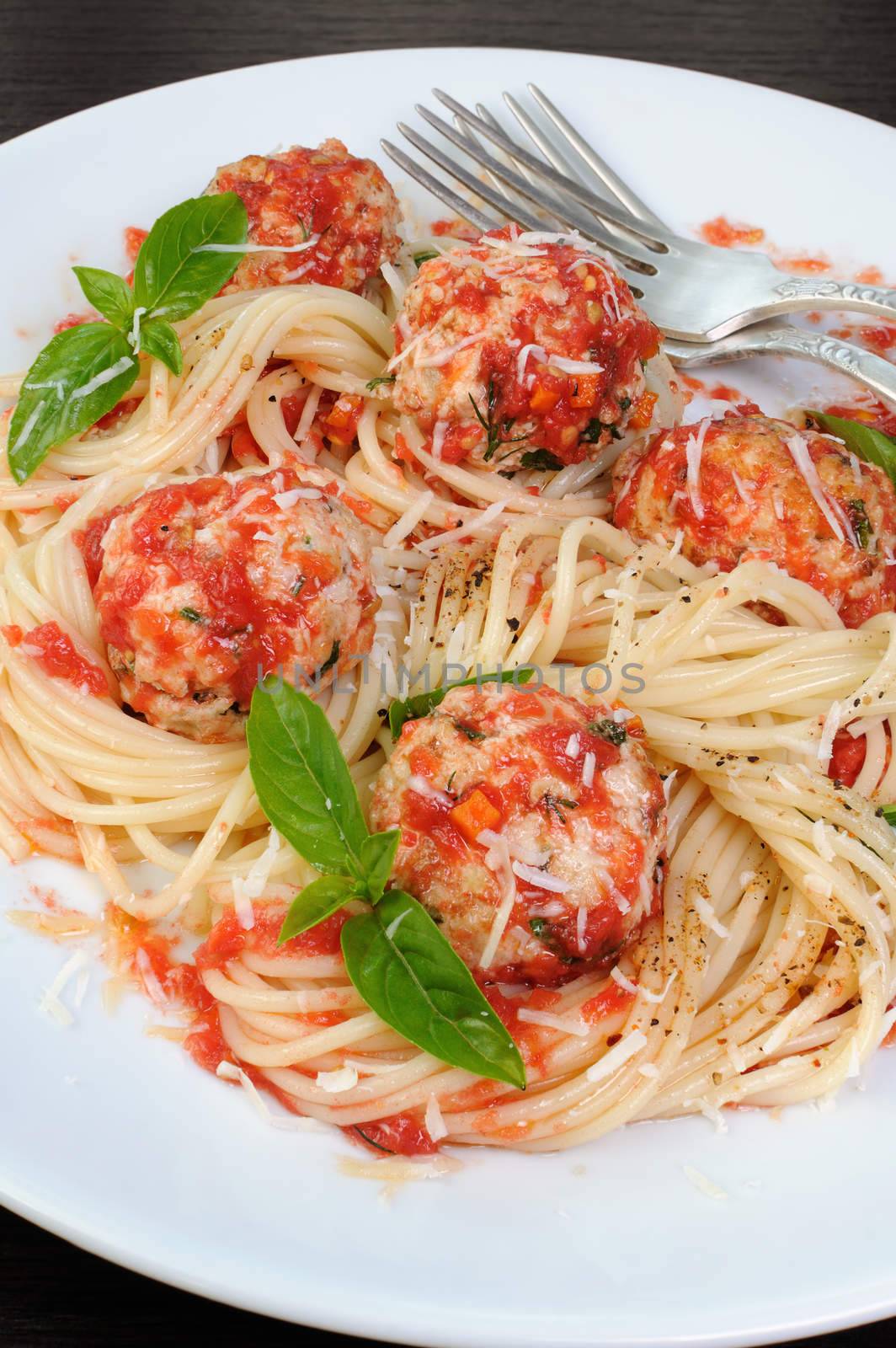 Pasta in tomato gravy with meatballs sprinkled Parmesan and basil