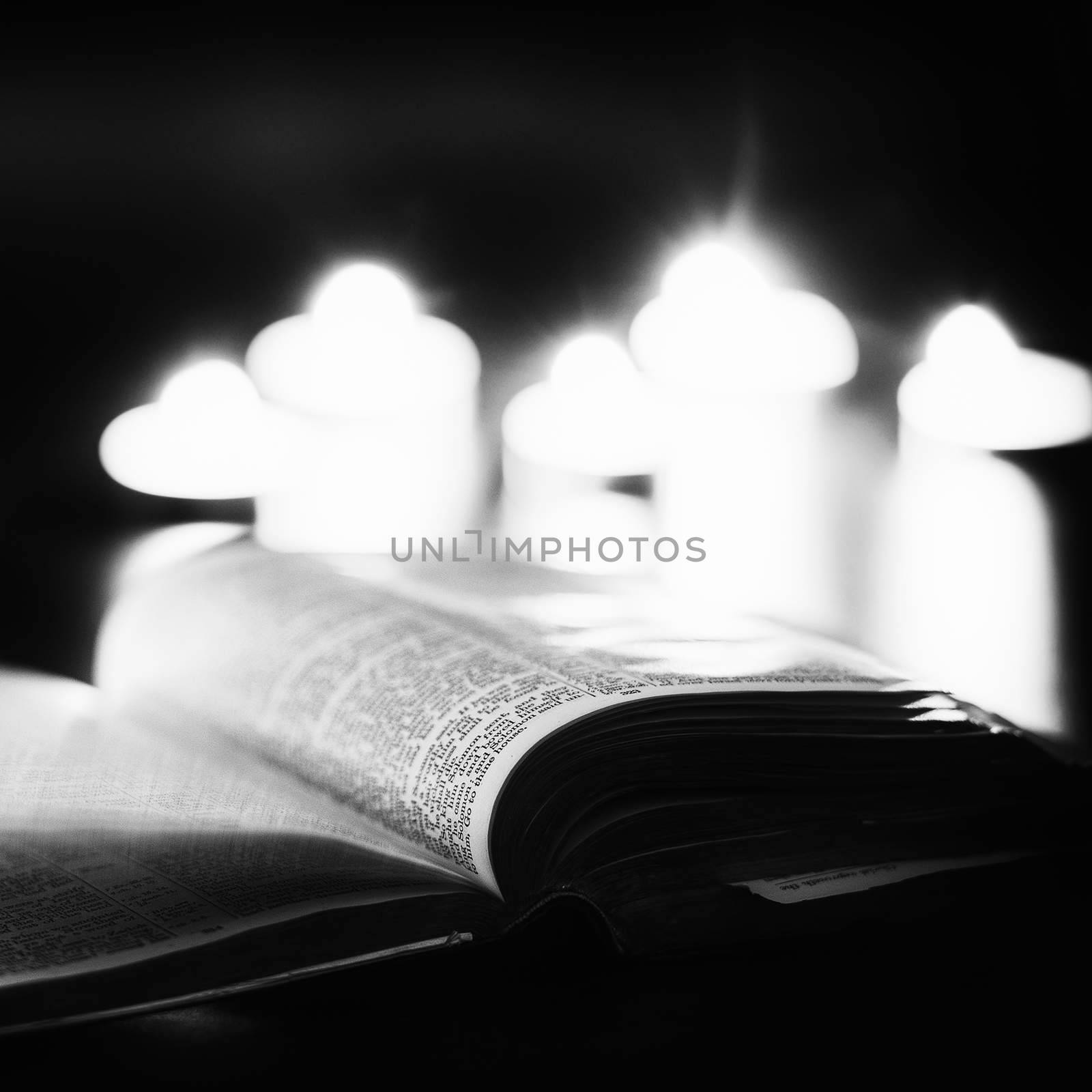 Bible with candles in the background. Low light high contrast black and white image.