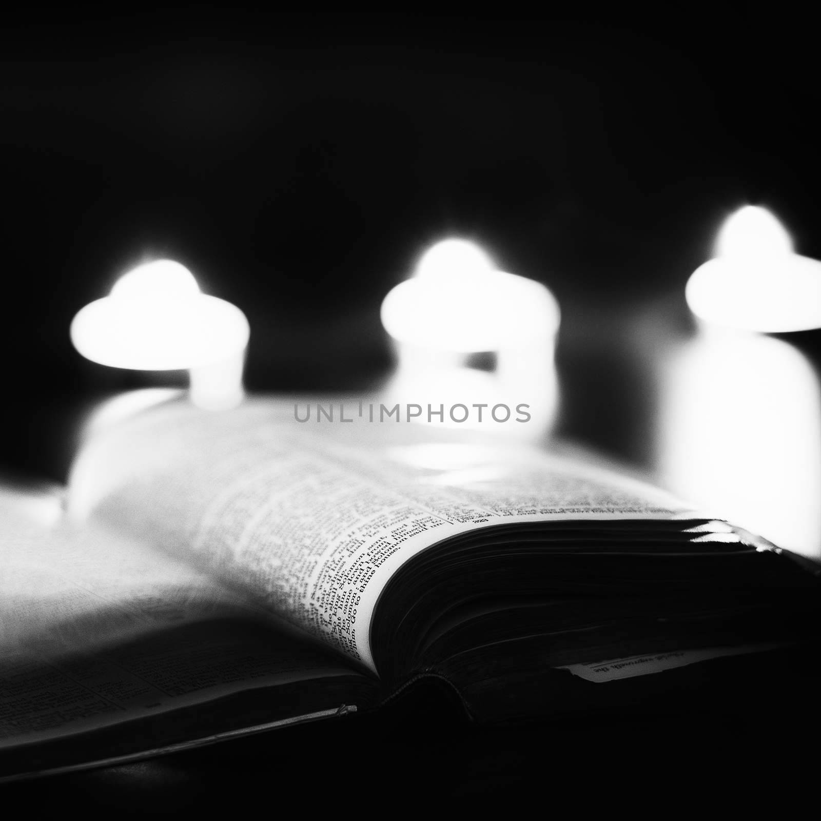 Bible with candles in the background. Low light high contrast black and white image.