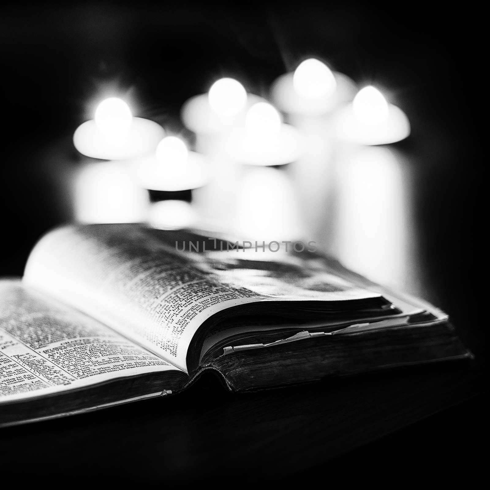Bible with candles in the background. Low light high contrast black and white image.