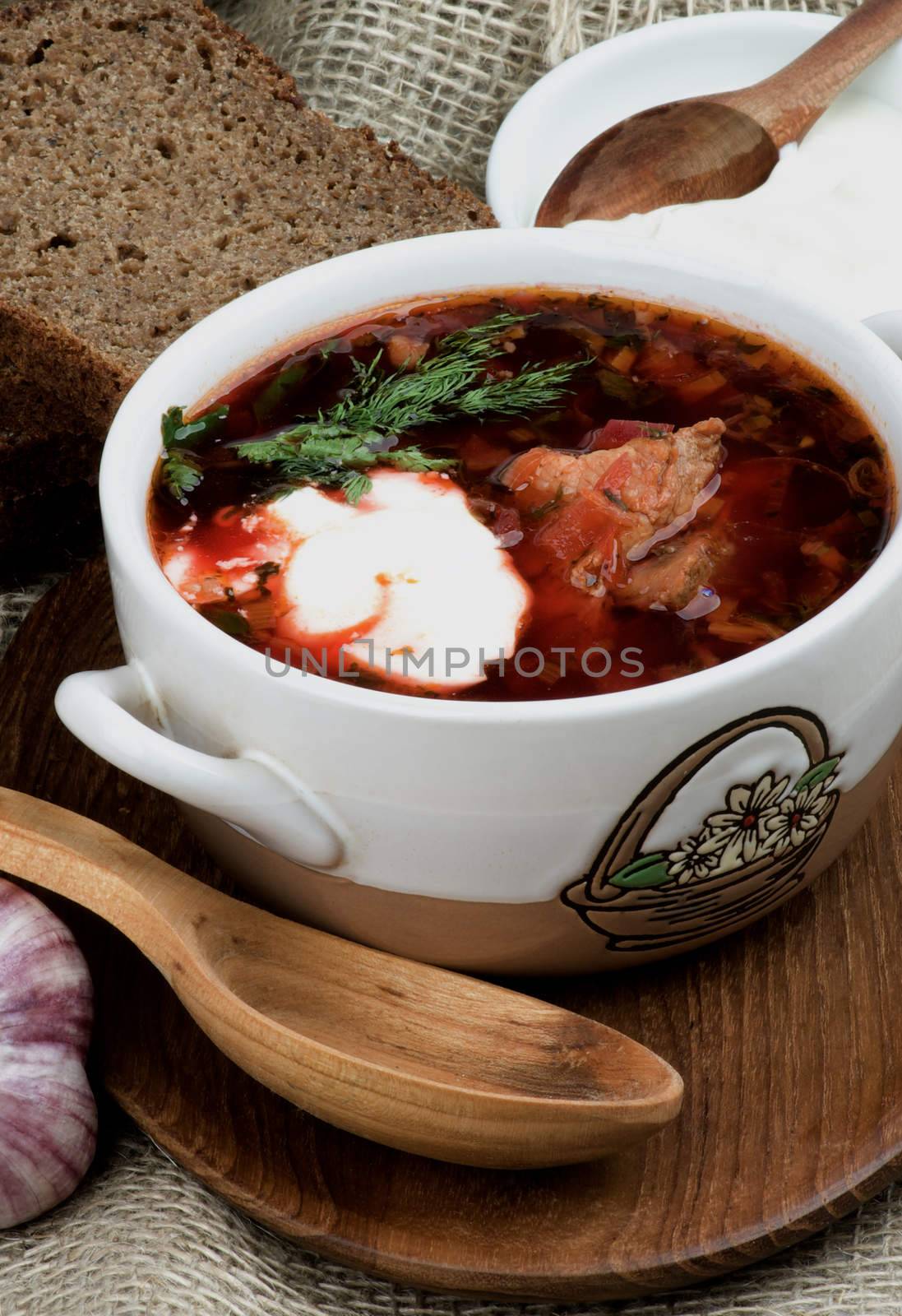 Ukrainian National Traditional Borscht Soup with Beet, Vegetables and Meat Arranged with with Brown Bread, Garlic and Sour Cream closeup