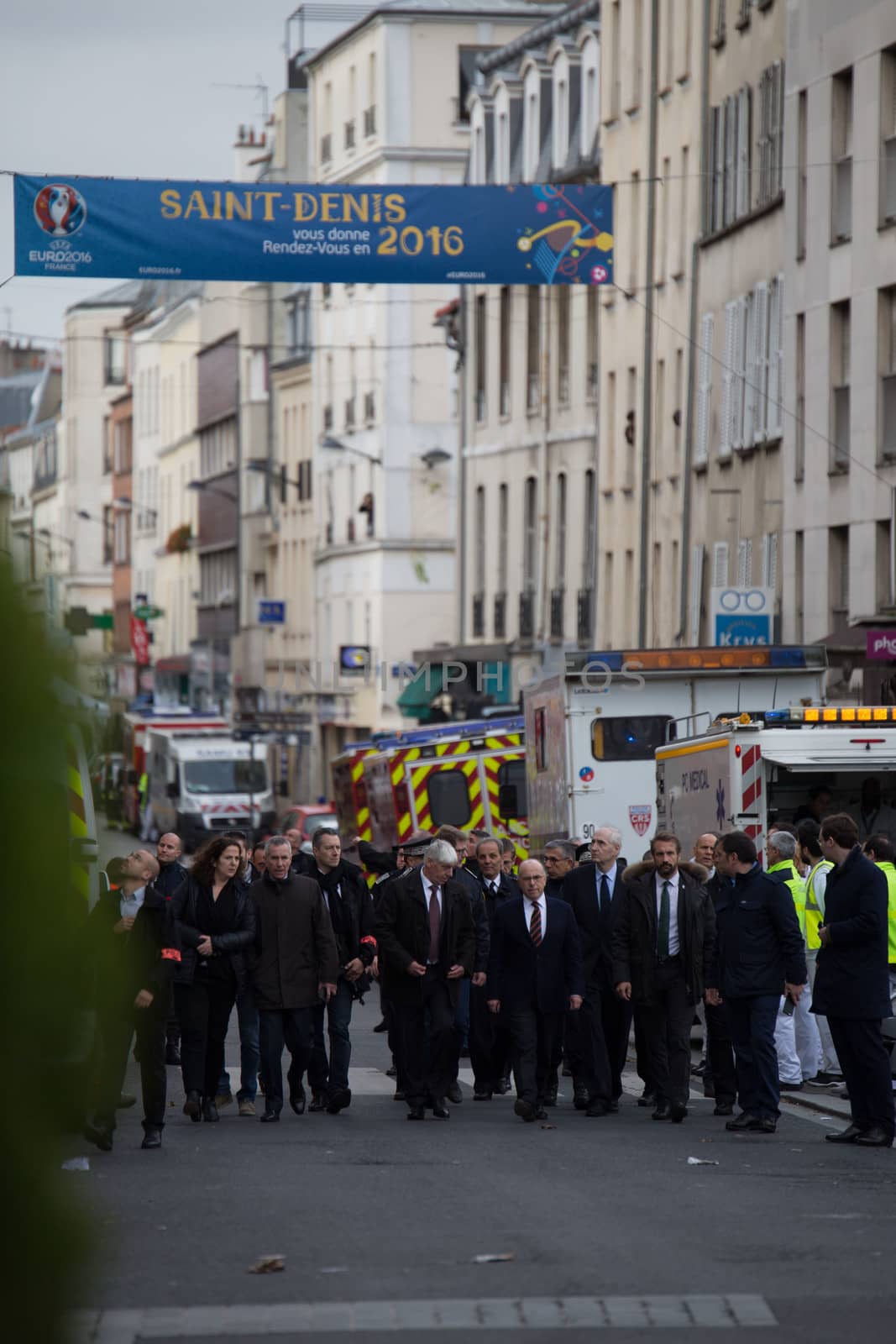 FRANCE, Saint-Denis: Politicians including French minister of the Interieur Bernard Cazeneuve are seen in a security perimeter set in the northern Paris suburb of Saint-Denis city center, on November 18, 2015, to secure the area after French Police special forces raid an appartment, hunting those behind the attacks that claimed 129 lives in the French capital five days ago. At least one person was killed in an apartment targeted in the operation aimed at the suspected mastermind of the attacks, Belgian Abdelhamid Abaaoud, and police had been wounded in the shootout.
