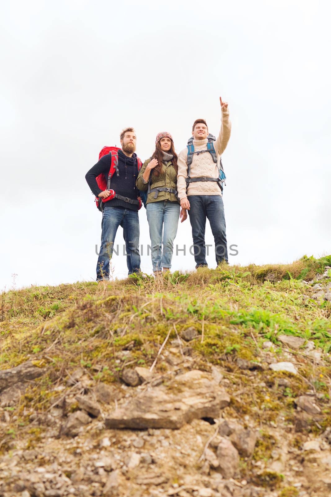 adventure, travel, tourism, hike and people concept - group of smiling friends with backpacks pointing finger outdoors