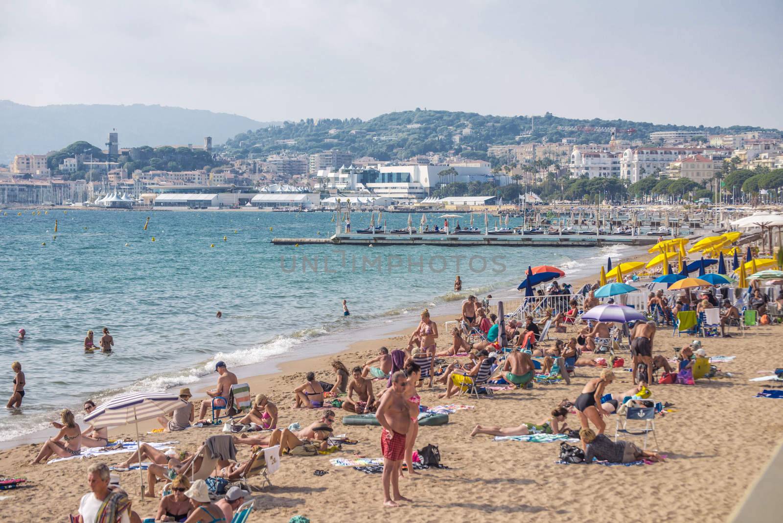 Cannes, France - September 27, 2013: People on the beach in Cannes.  The famous beach on the Croisette, known for its cinema festival. People are sun bathing, swiming and resting 8 mounth in the year.