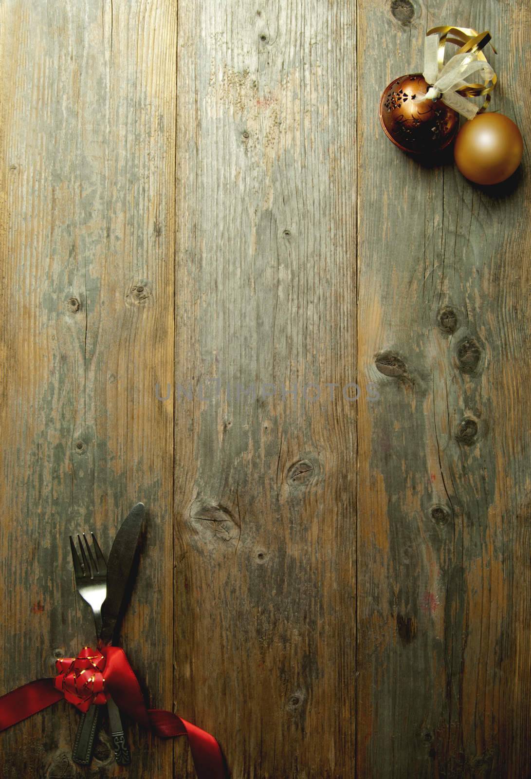 Wooden  background menu with cutlery tied in red ribbon and xmas baubles 