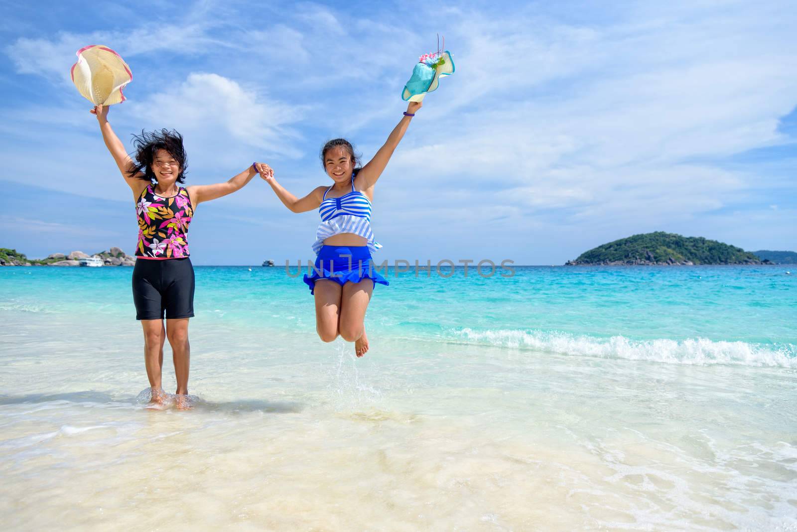Mother and daughter wear a swimsuit playing in the blue sea near the beach with happiness during summer at Koh Miang Island, Mu Ko Similan National Park, Phang Nga province, Thailand