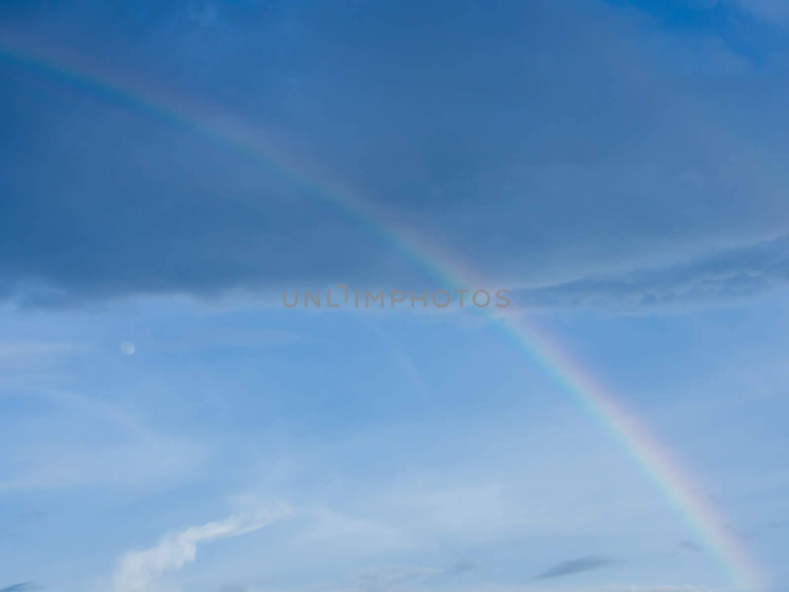 rainbow in the sky with the moon after rain before sunset