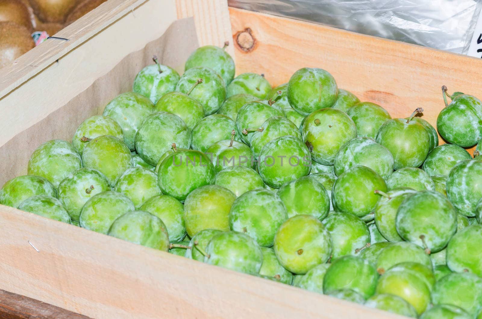 Fresh green fruits on a market in a wooden box.
