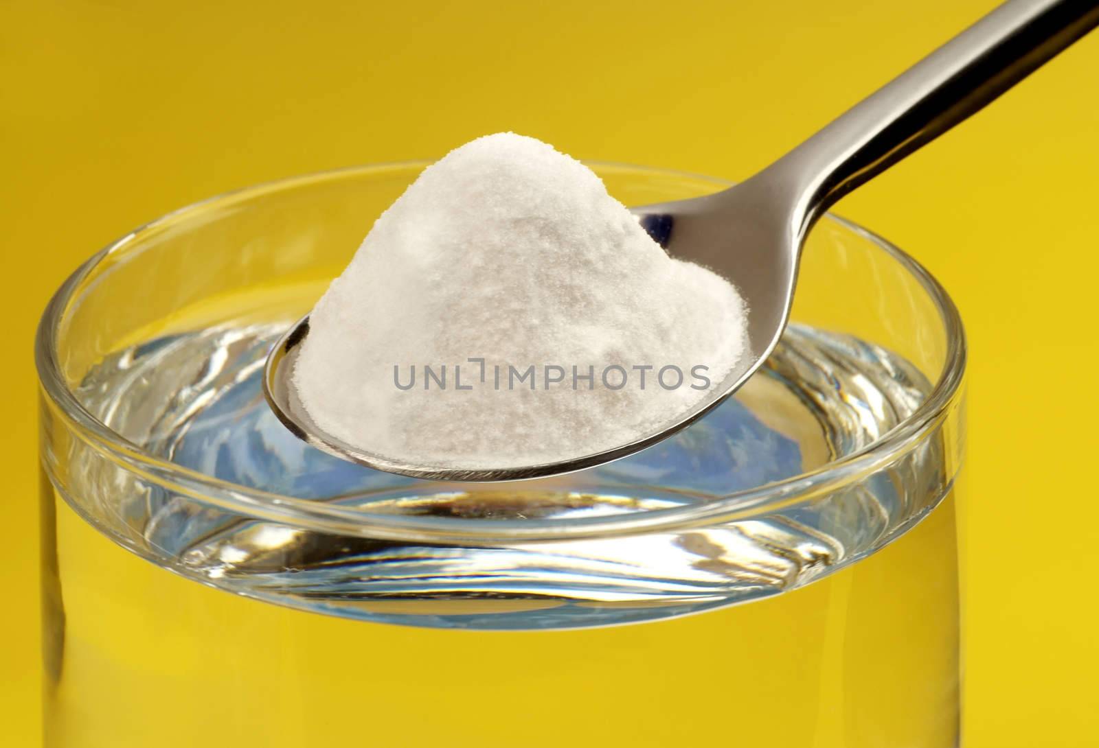 Spoon of baking soda above a glass of water