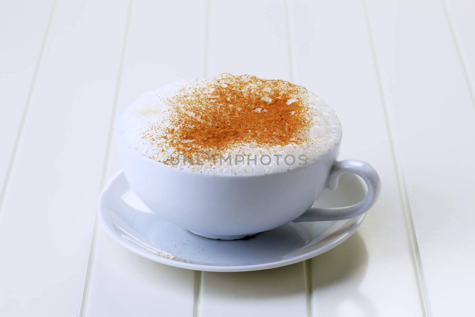 Cup of cappuccino with rich milk froth and nutmeg on top