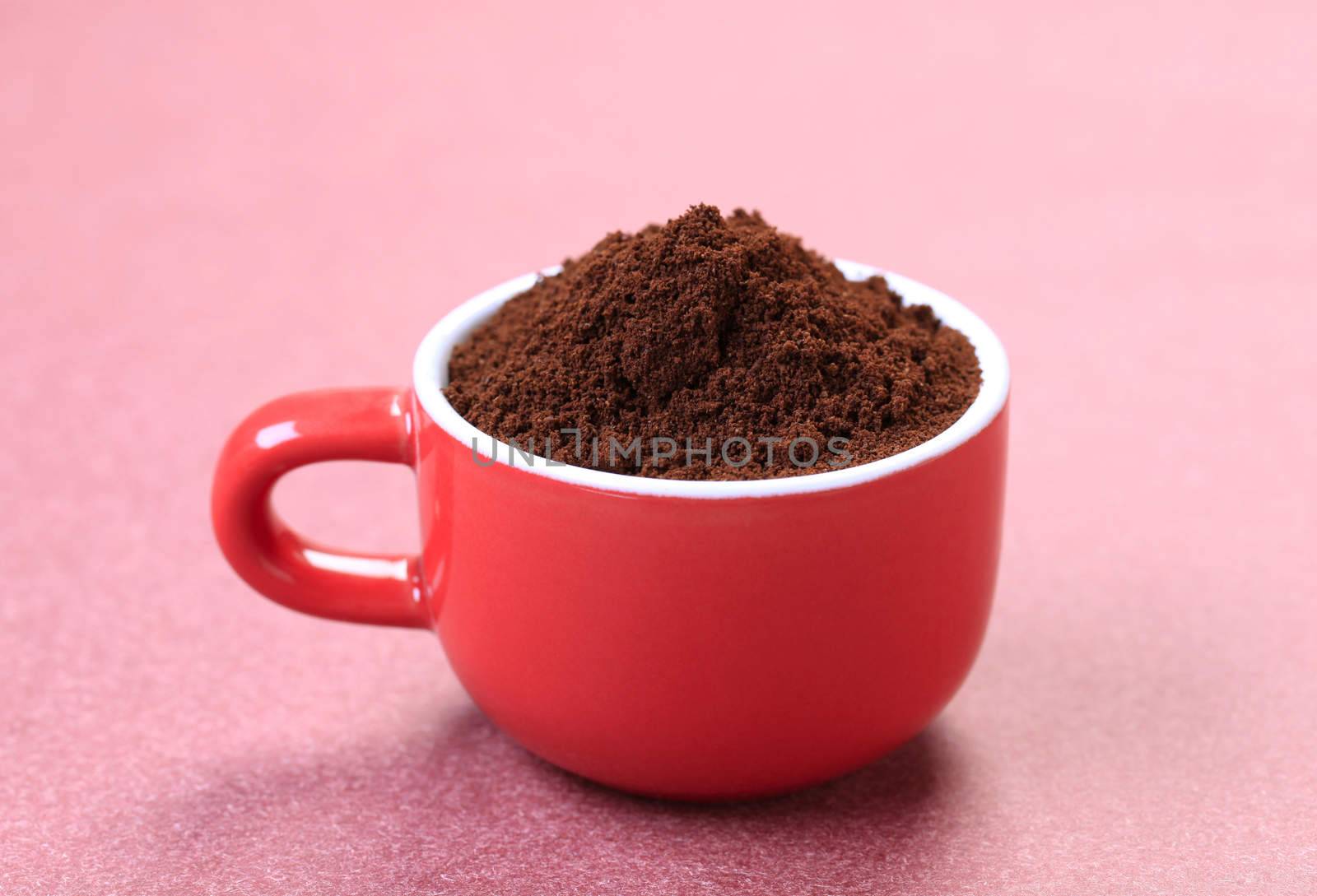 Heap of freshly ground coffee in a red cup