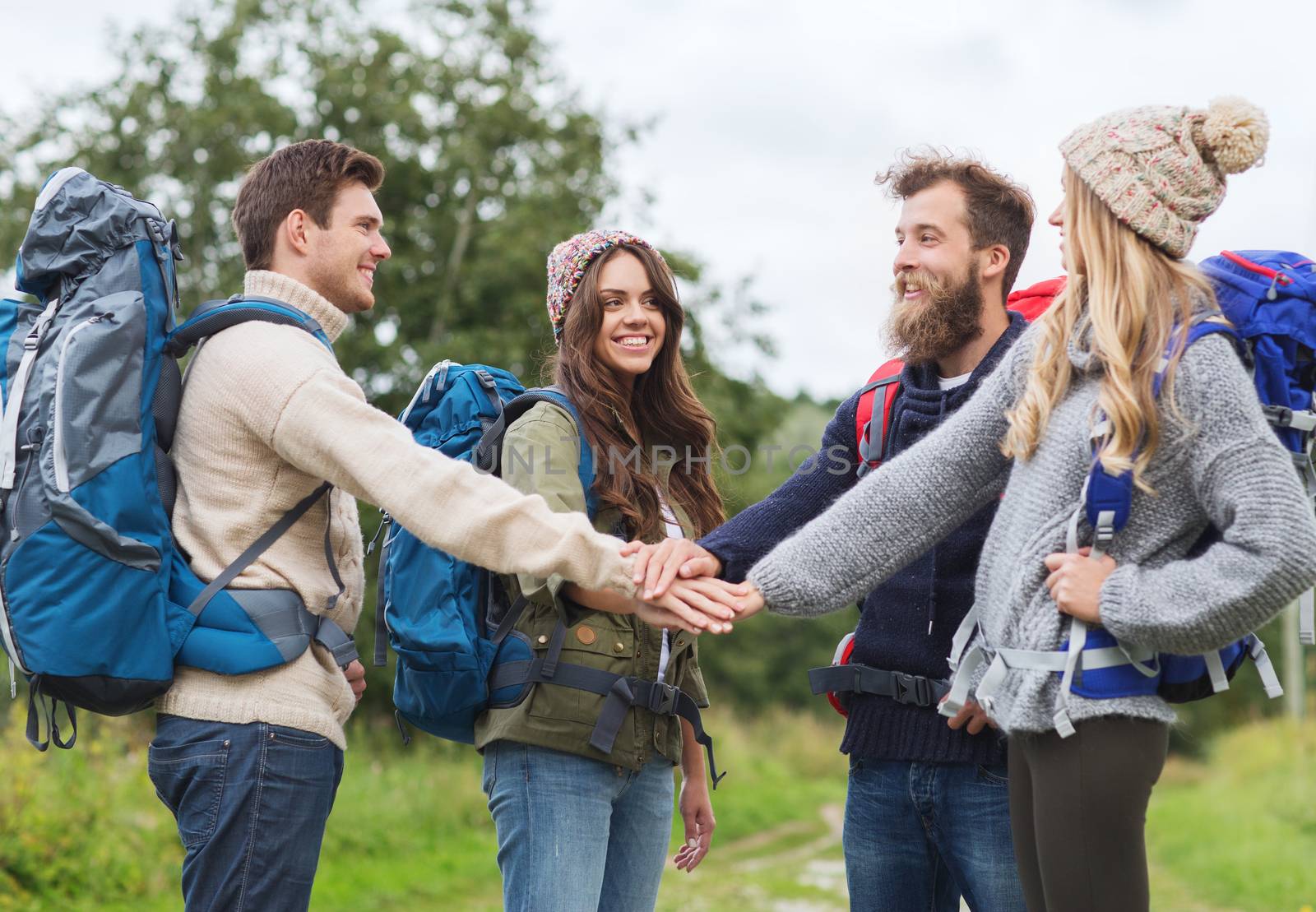 group of smiling friends with backpacks hiking by dolgachov